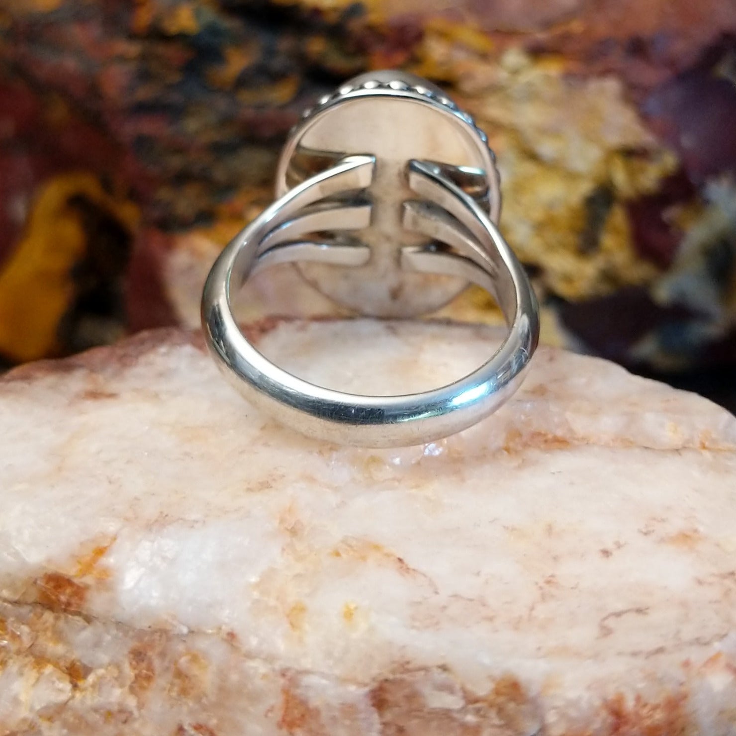 Sugilite framed by dotted accents, raised on the thin, sterling silver band.