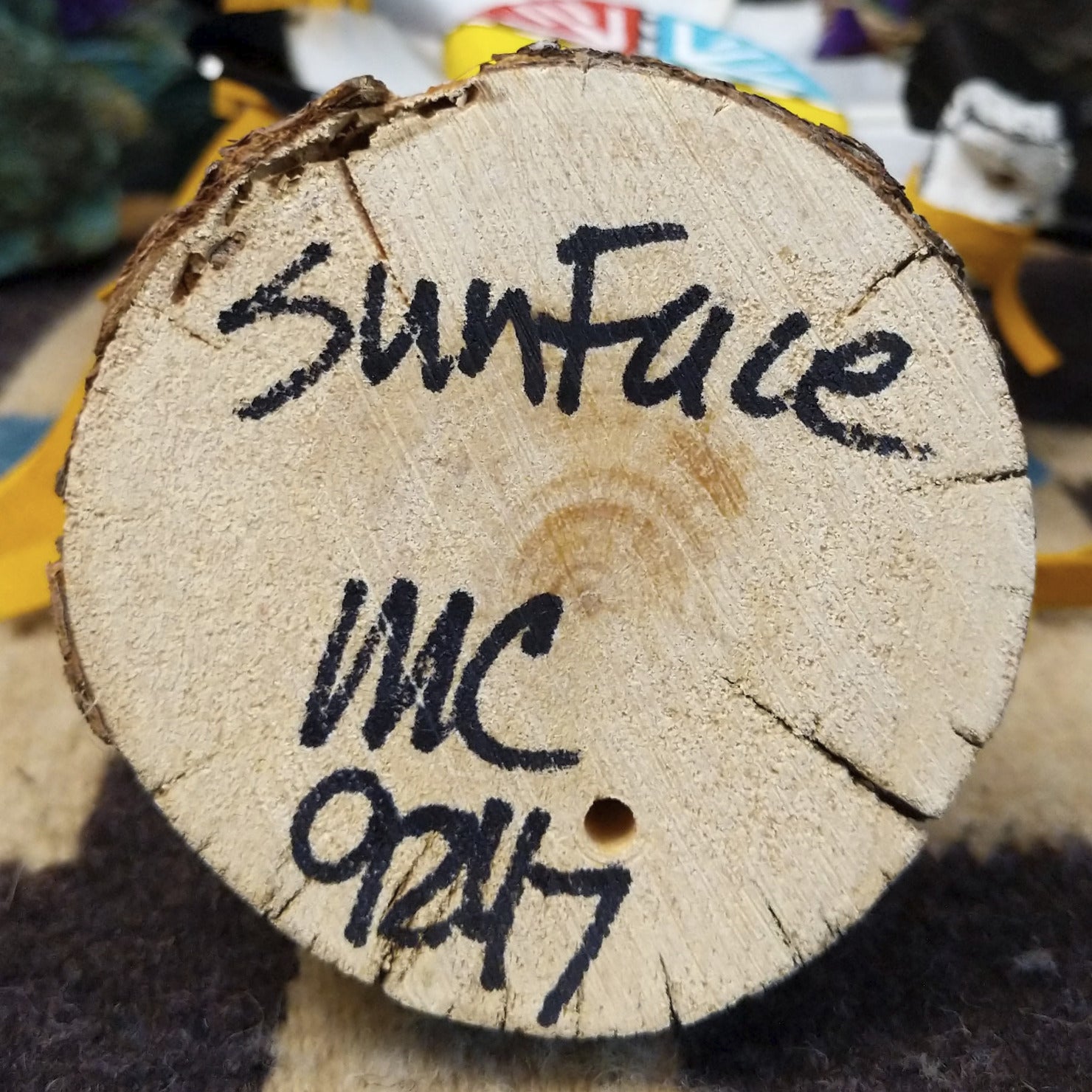 Underside of M. C. sunface kachina doll showing handwritten signature and label on wood base.