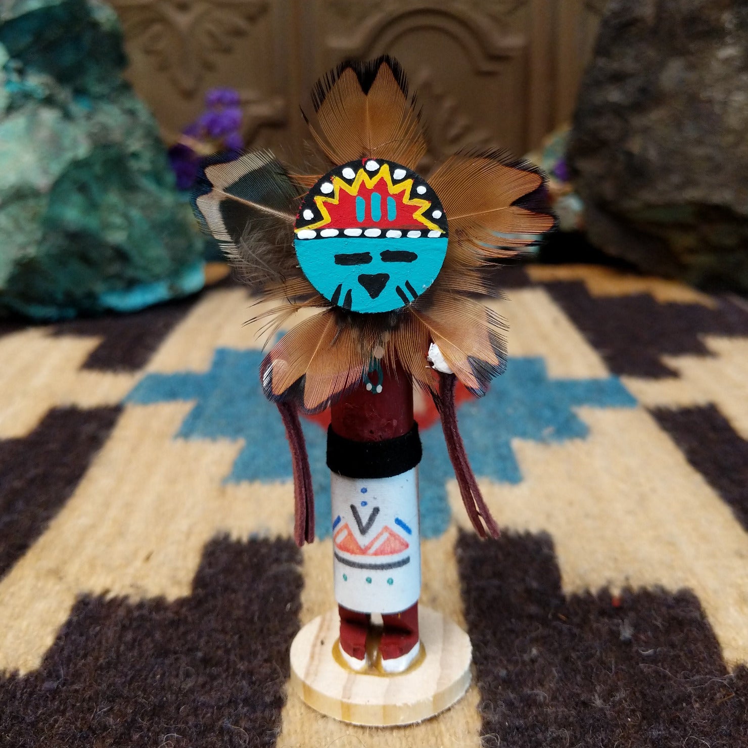 Mini Sunface kachina by Rosalind Grey with turquoise circular face, feathered halo, and white geometric-patterned garment.
