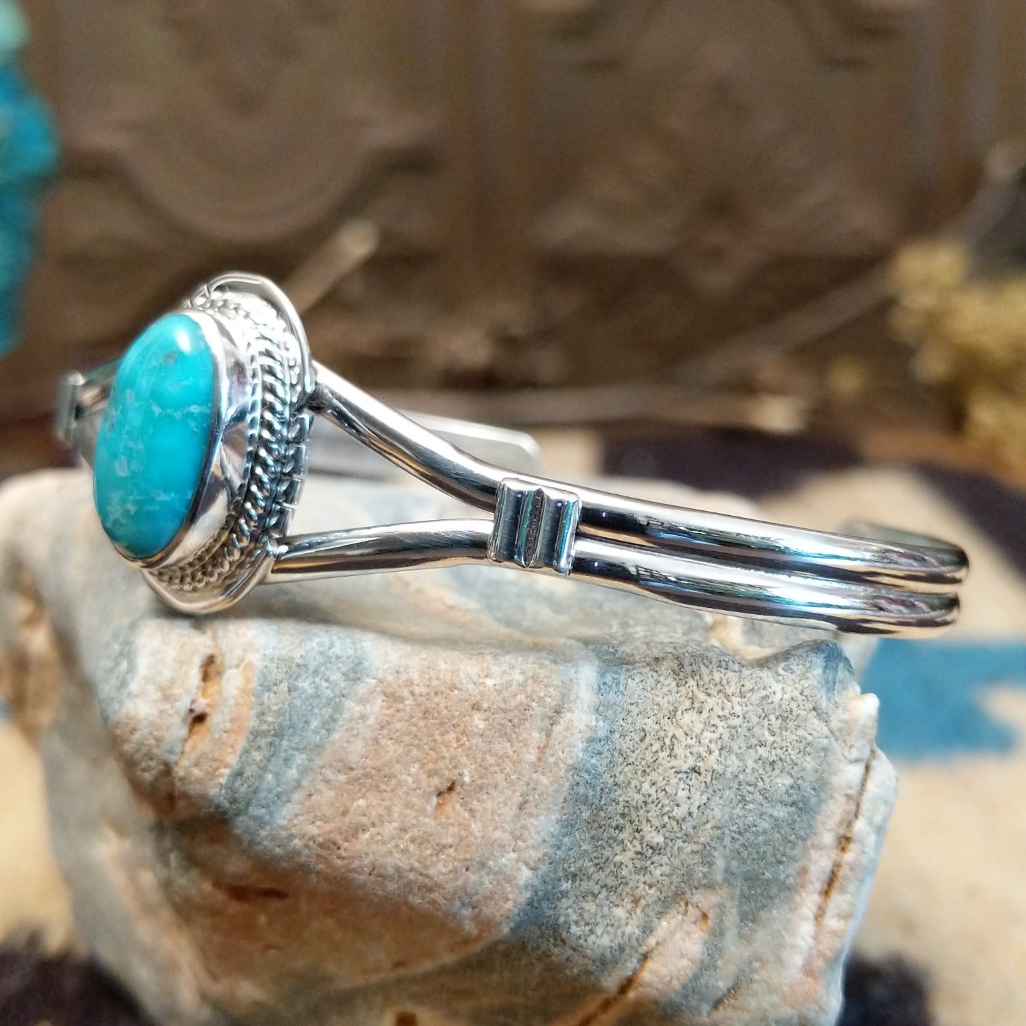Sterling silver cuff with turquoise set in an oval bezel, framed by twisted rope and incised setting.