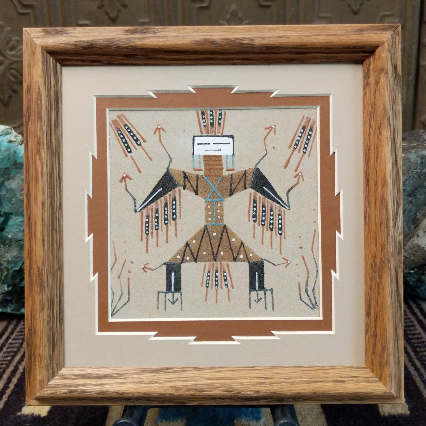 Framed Navajo sand painting of Thunder People with lightning-like details and wing-shaped elements.