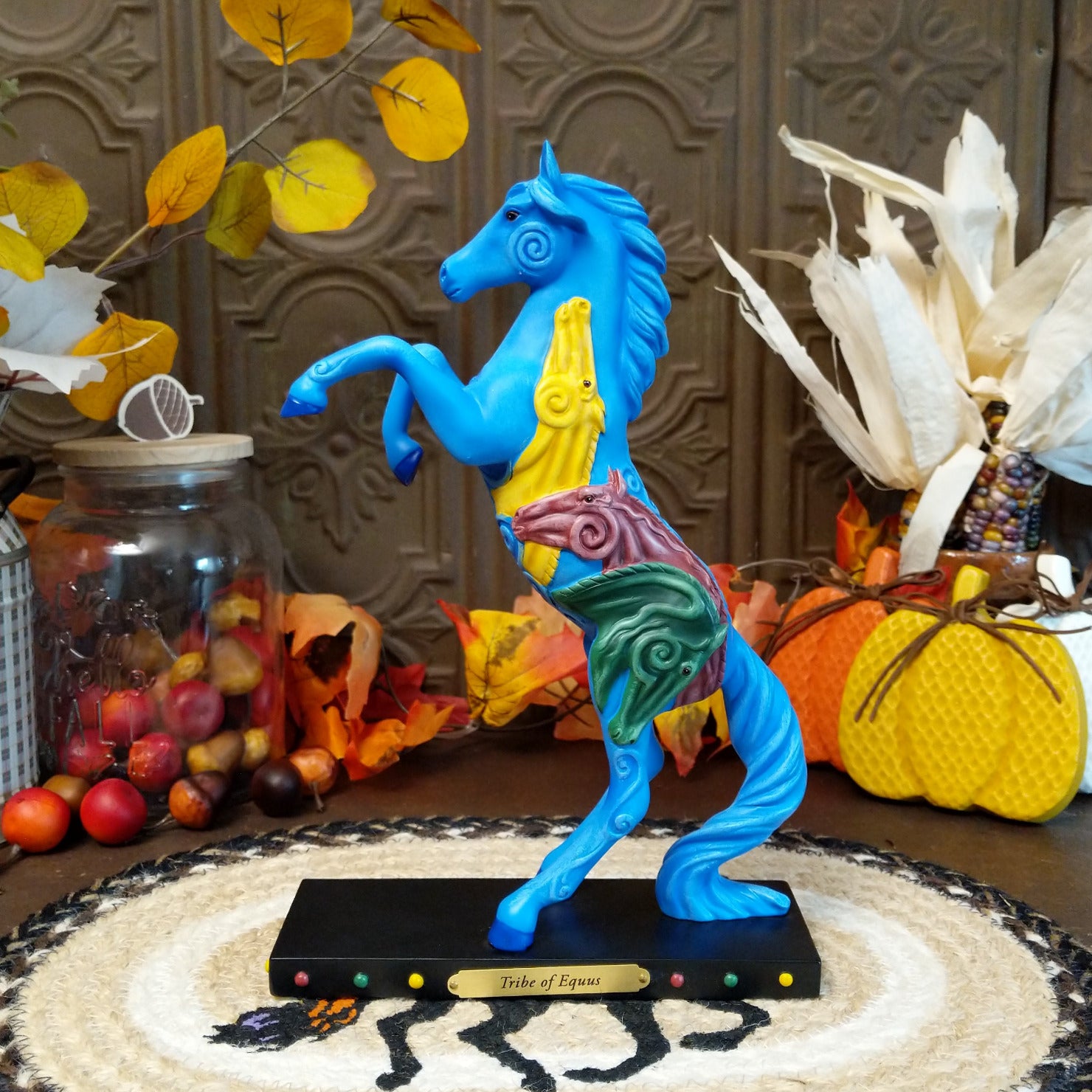 Pony in a rearing position painted blue with yellow, purple, and green horse heads on the body.