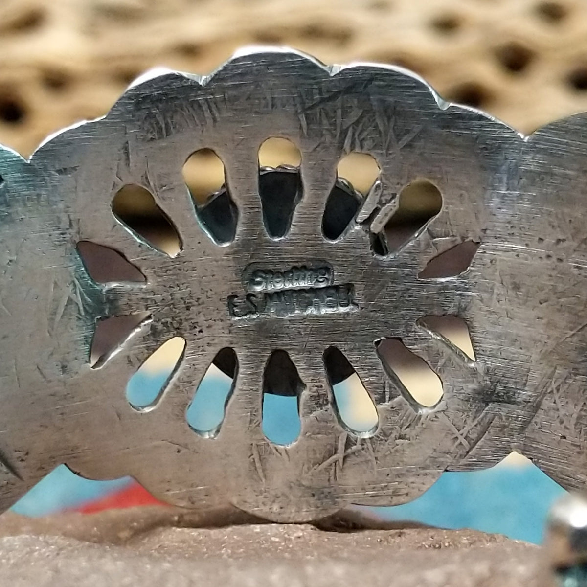 Turquoise cuff by Eugene Mitchell, featuring an oval blue turquoise stone set in a handcrafted sterling silver cuff with an intricate floral cutout design; artisan and Sterling Silver stamp.