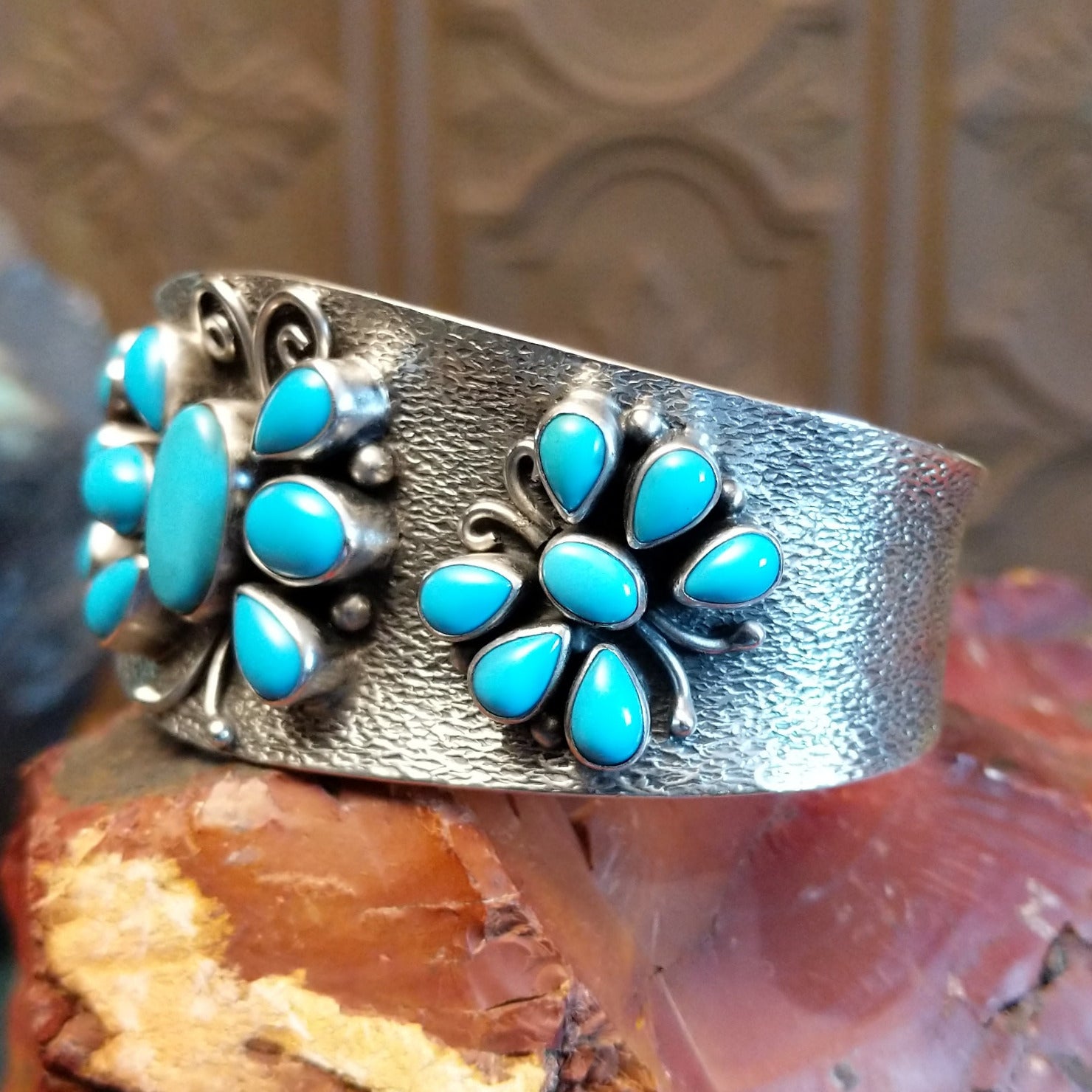 Sterling silver cuff bracelet features turquoise set in bezels creating butterfly motifs along the hammered surface.