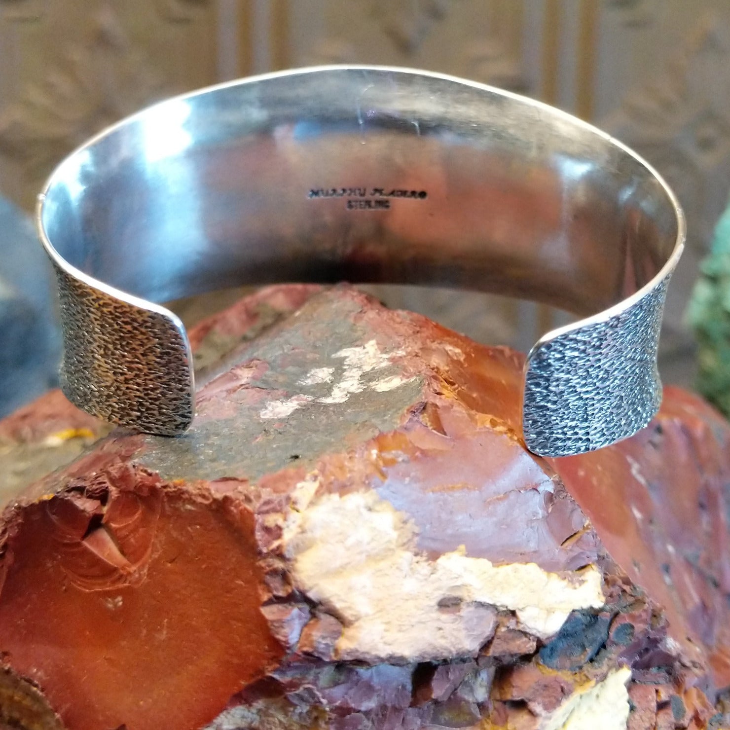 Sterling silver cuff bracelet features turquoise set in bezels creating butterfly motifs along the hammered surface.