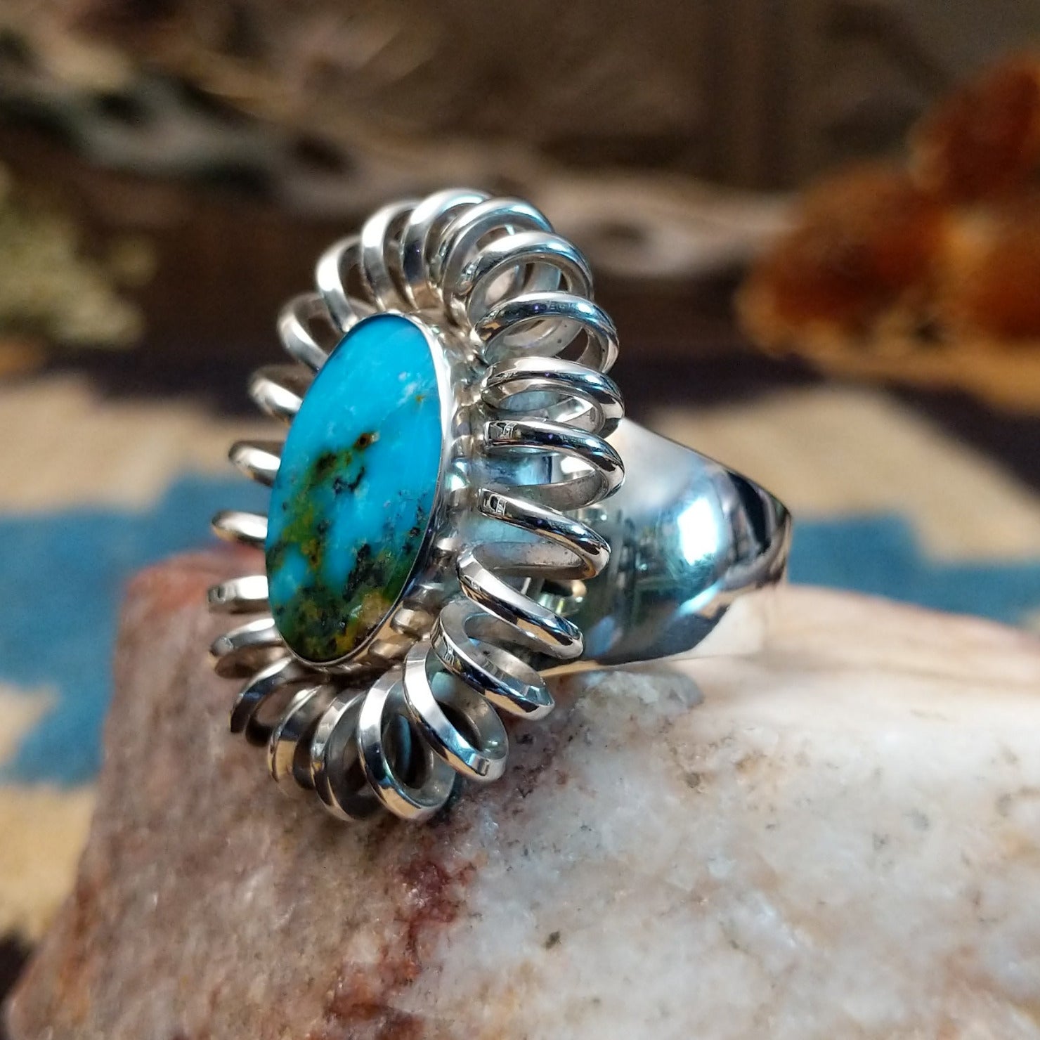 Sterling silver ring with turquoise set in the large oval bezel, framed by coiled silverwork.