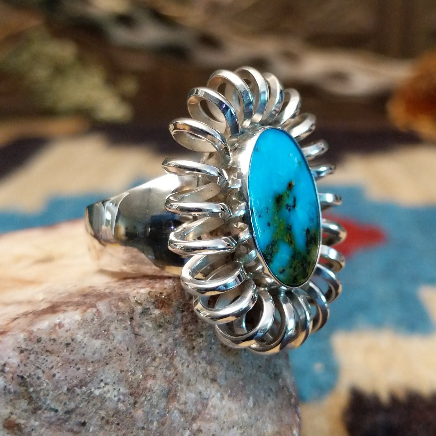 Sterling silver ring with turquoise set in the large oval bezel, framed by coiled silverwork.