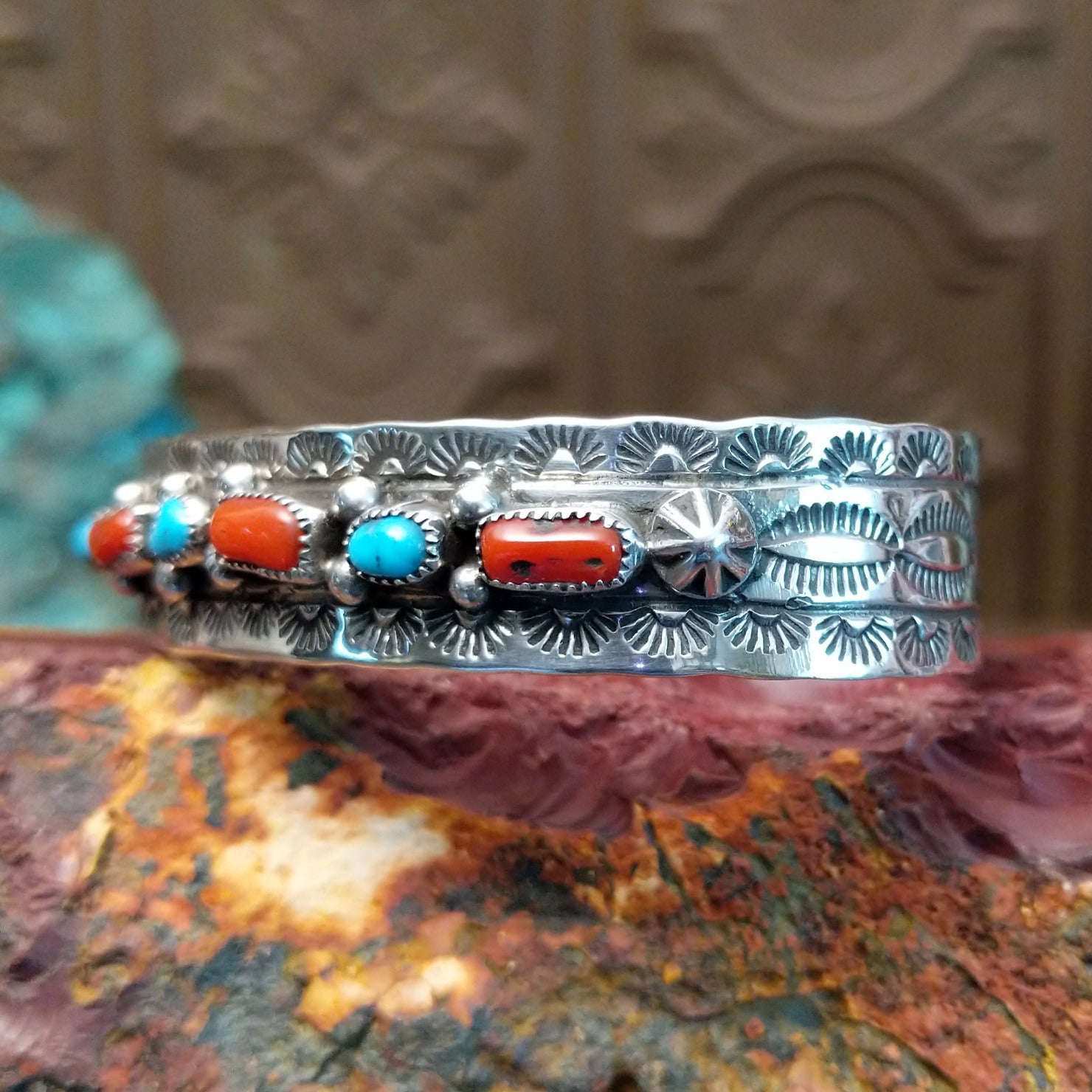 Sterling silver cuff featuring turquoise and coral set in notched bezels.