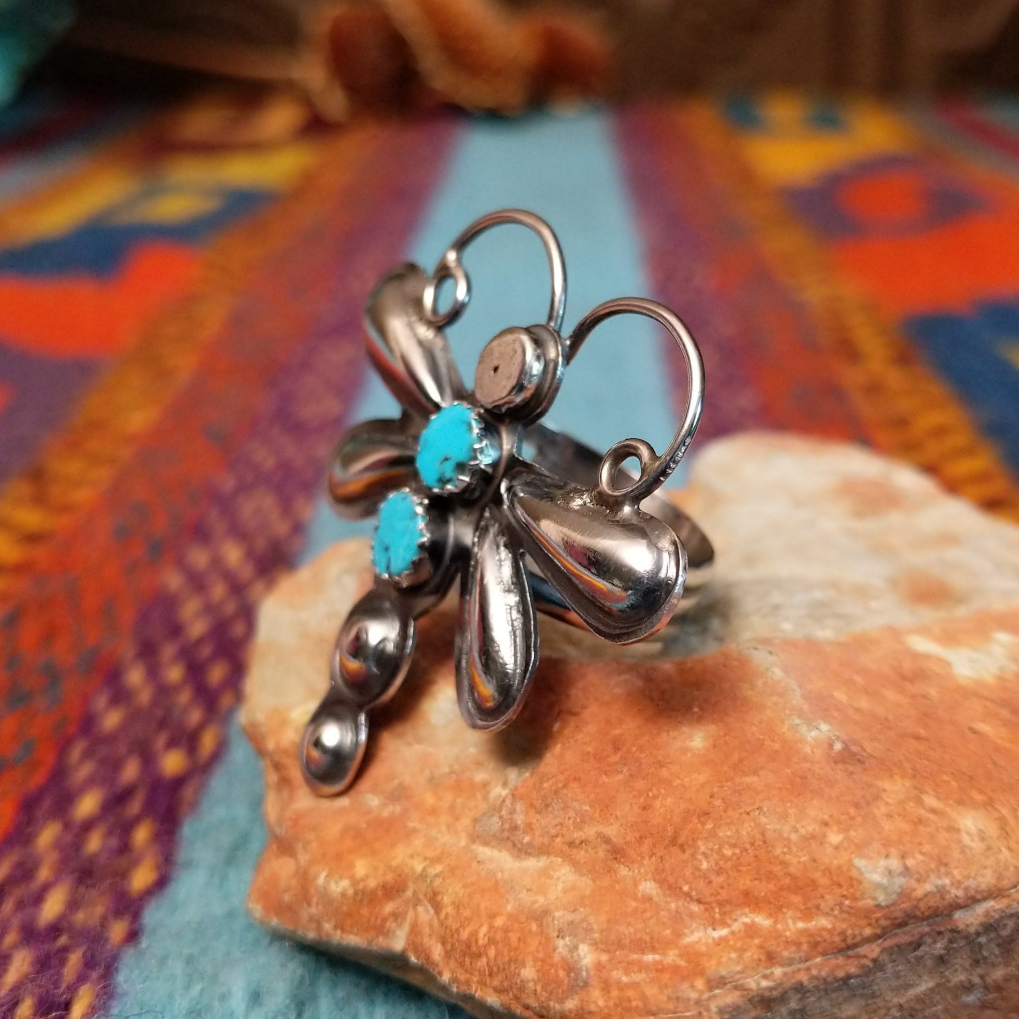Turquoise Dragonfly Ring by Tim Yazzie featuring two turquoise stones set in Sterling Silver with polished wings, curled antennae, and dimensional silver accents; side view.