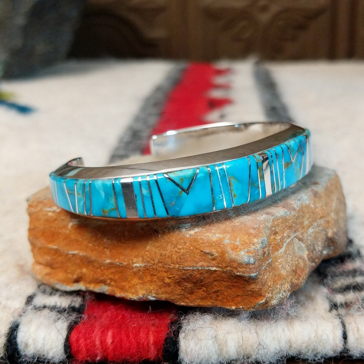 Silver cuff by Raymond Coriz featuring vibrant turquoise inlay with natural matrix and intricate geometric silver channel designs; side view.