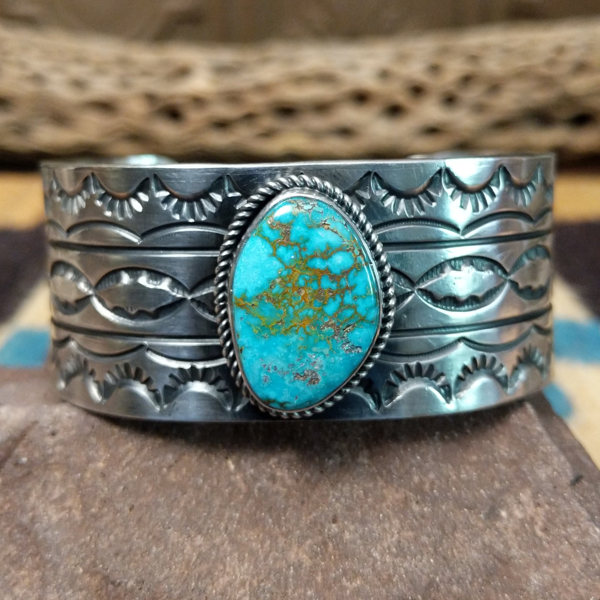 Turquoise Mountain turquoise cuff by E. Piaso, featuring a blue turquoise stone with a natural brown matrix set in a handcrafted wide sterling silver cuff.