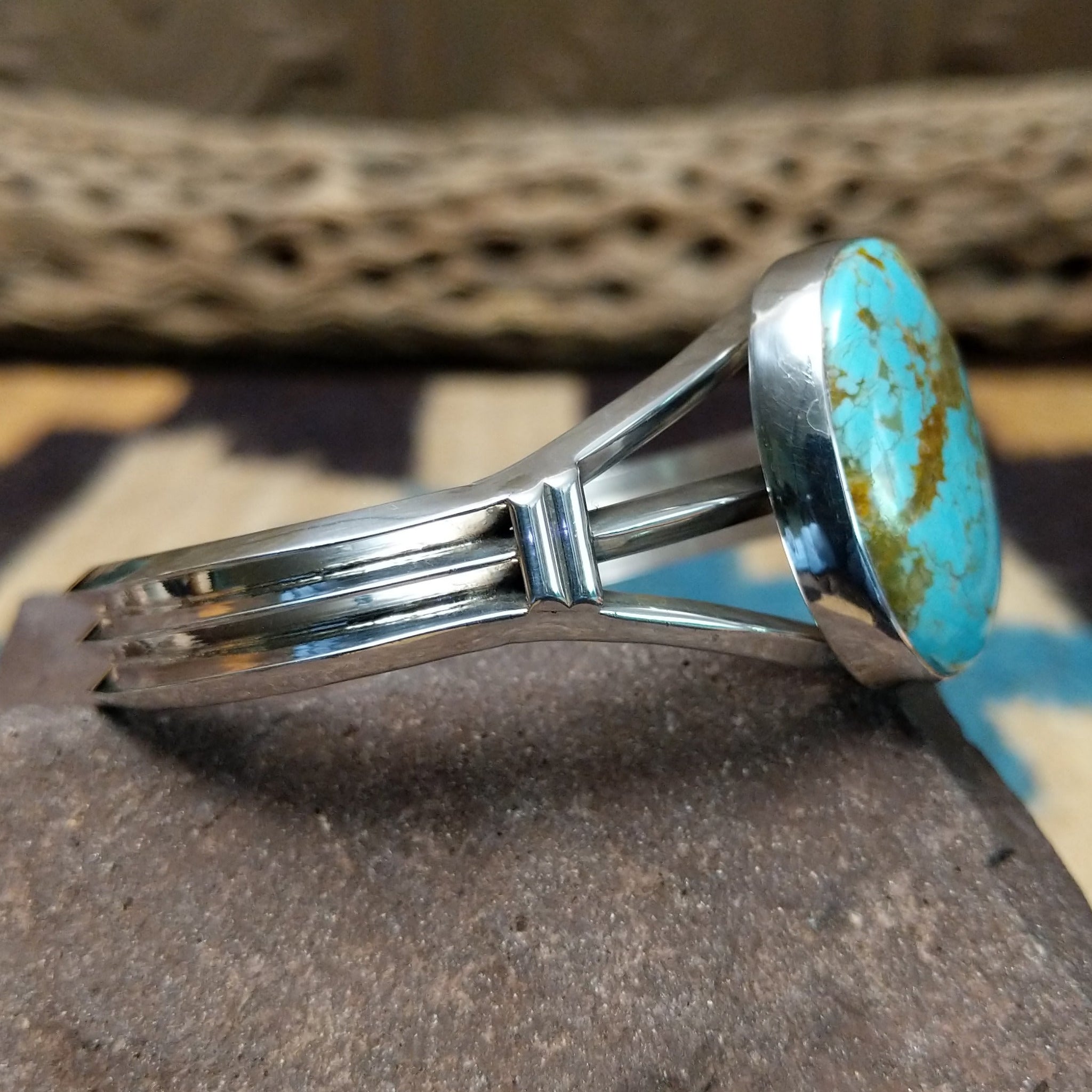 Turquoise Mountain turquoise cuff by Lucy Jake, featuring a blue turquoise stone with a natural brown matrix set in a handcrafted sterling silver cuff; side view.
