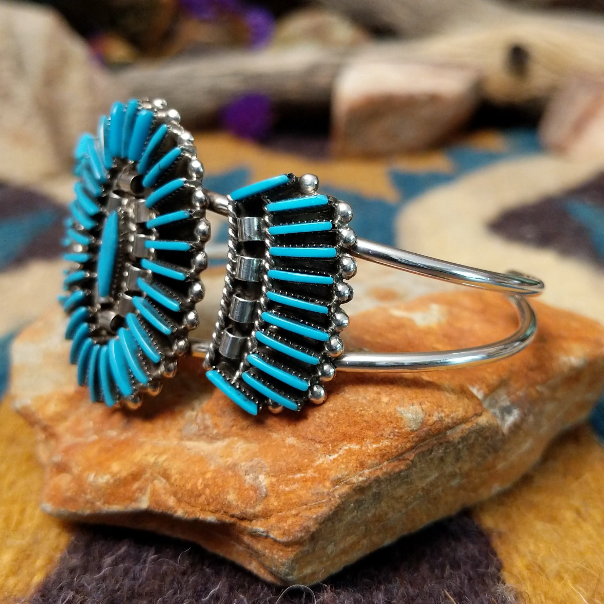 Handcrafted sterling silver cuff by Barton Cooeyate featuring a turquoise needlepoint concho centerpiece with matching side conchos, twisted rope detailing, silver bead accents, and a triple-shank cuff; side view.