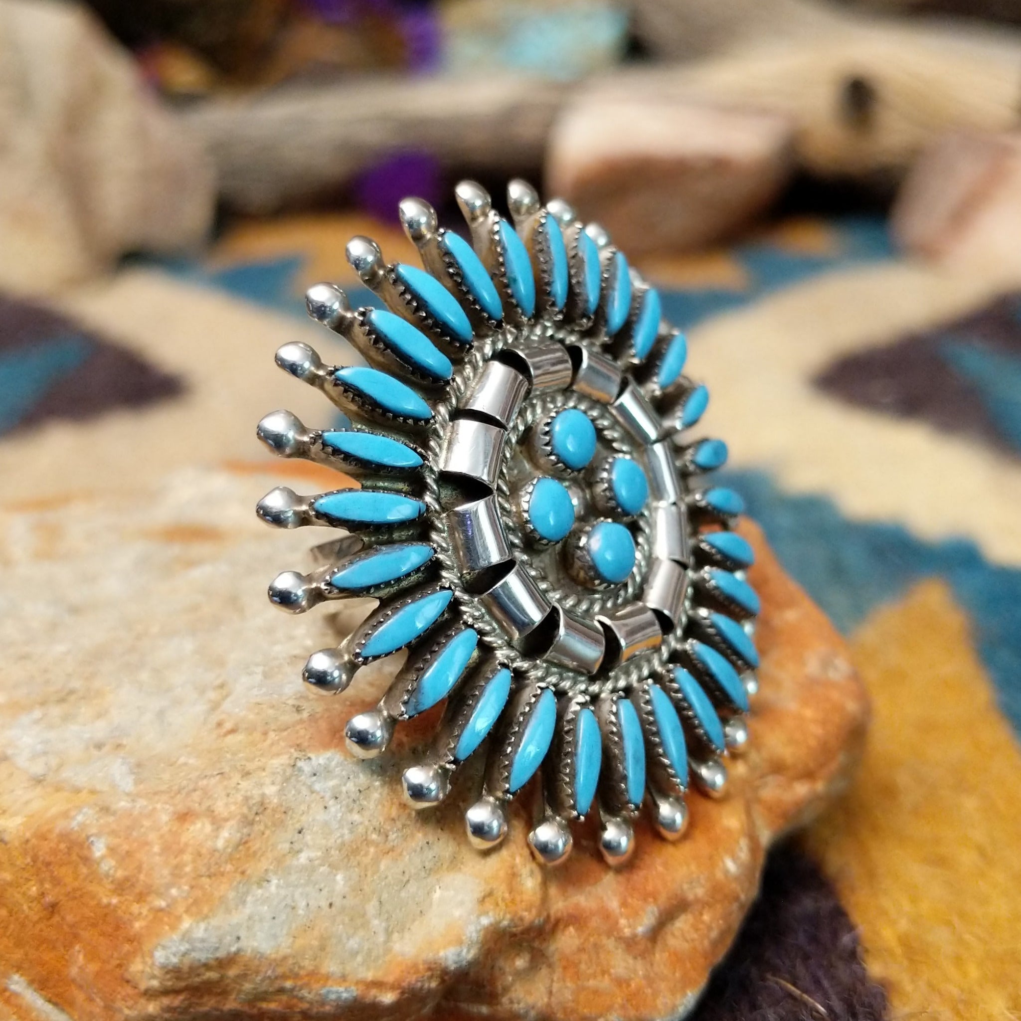 Handcrafted sterling silver Zuni concho ring featuring a turquoise needlepoint sunburst design with marquise-cut turquoise stones surrounding a central cluster of round turquoise cabochons, accented by polished silver details and twisted rope borders; side view.