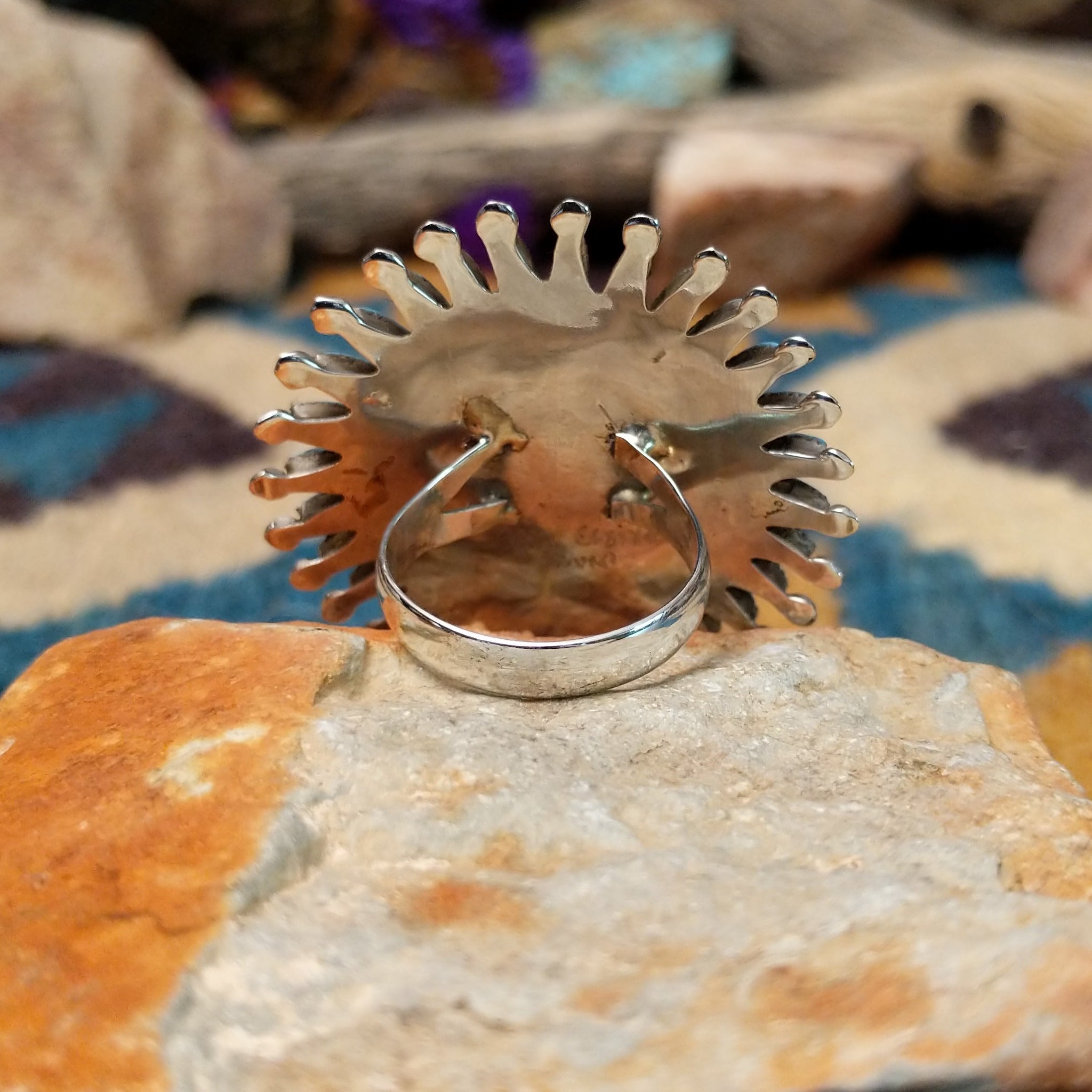 Handcrafted sterling silver Zuni concho ring featuring a turquoise needlepoint sunburst design with marquise-cut turquoise stones surrounding a central cluster of round turquoise cabochons, accented by polished silver details and twisted rope borders; underside view.