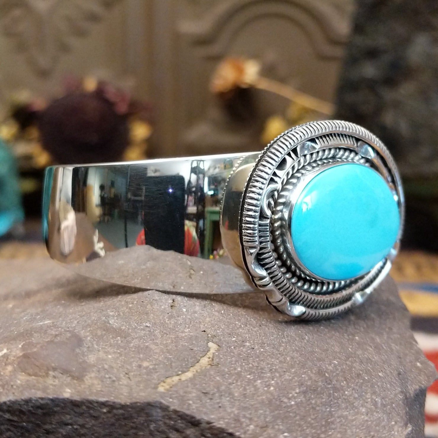 Silver cuff featuring an oval turquoise stone set in an intricate layered silver setting.