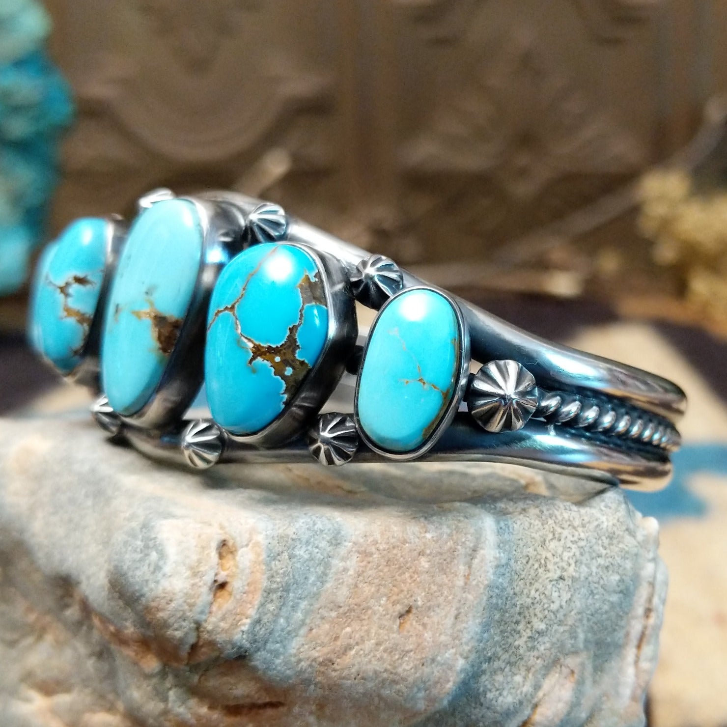 Sterling silver cuff bracelet with a quintet of turquoise set in bezels, framed by dotted and twisted rope accents.