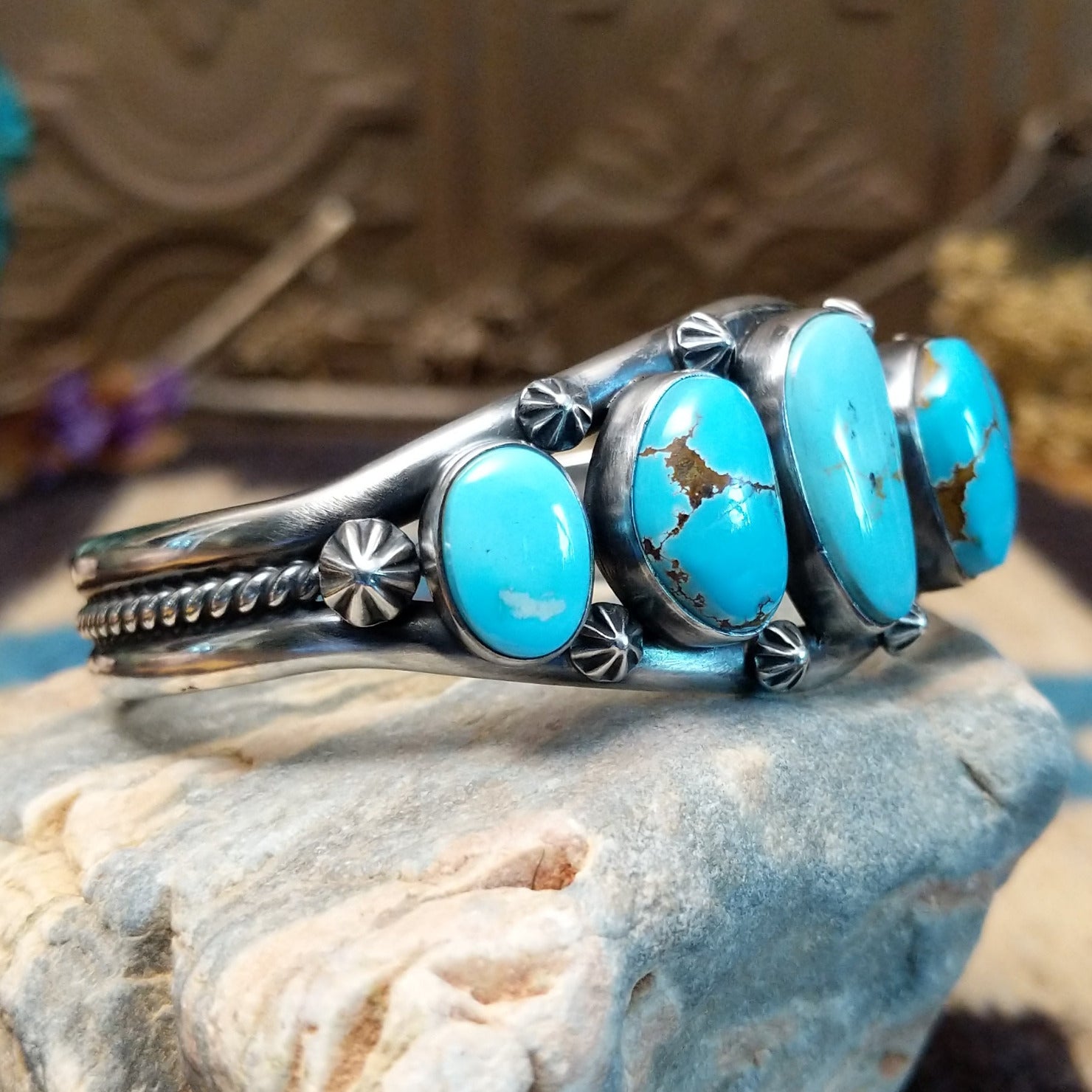 Sterling silver cuff bracelet with a quintet of turquoise set in bezels, framed by dotted and twisted rope accents.