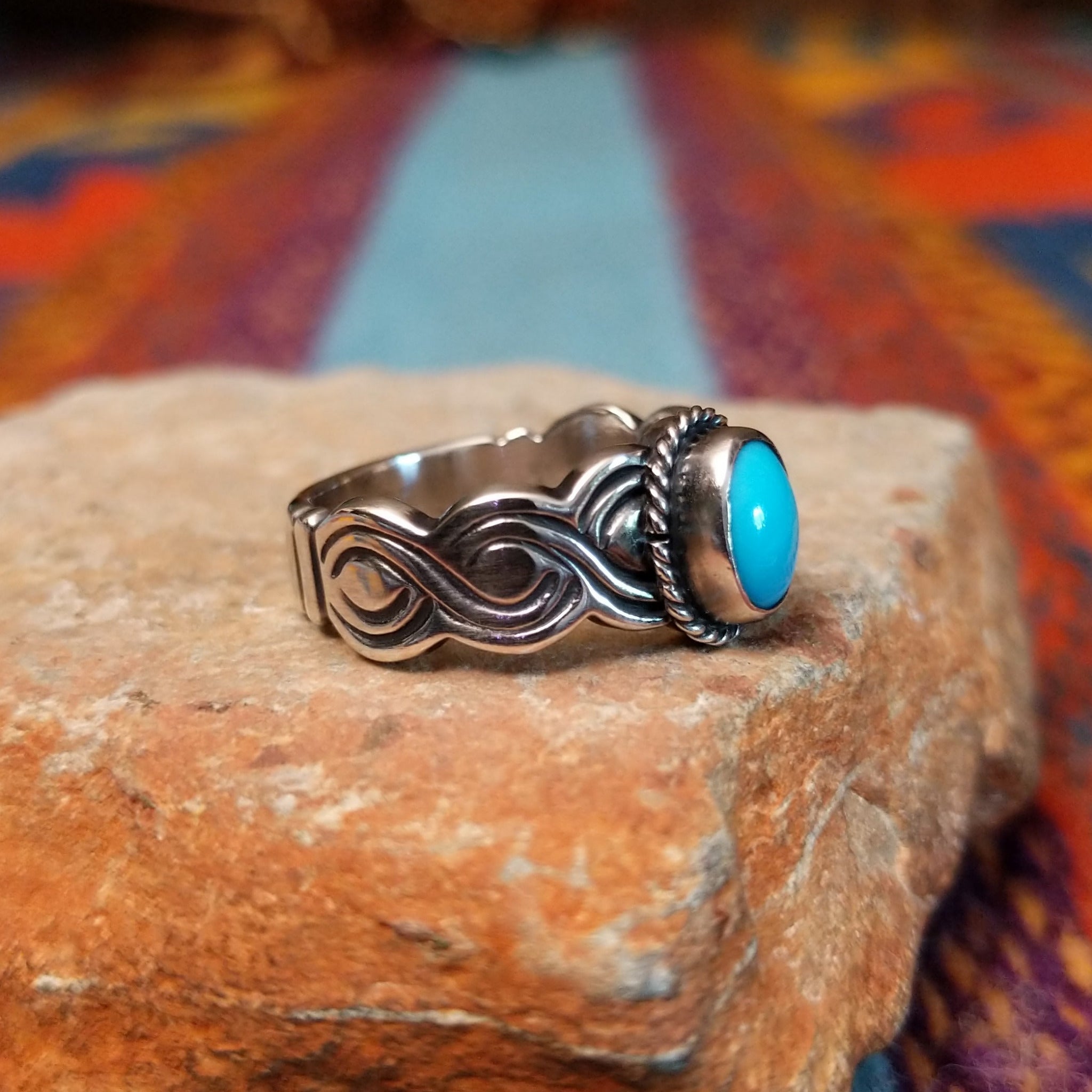 Turquoise ring by Raymond Coriz with oval stone, twisted border, and curved silverwork.