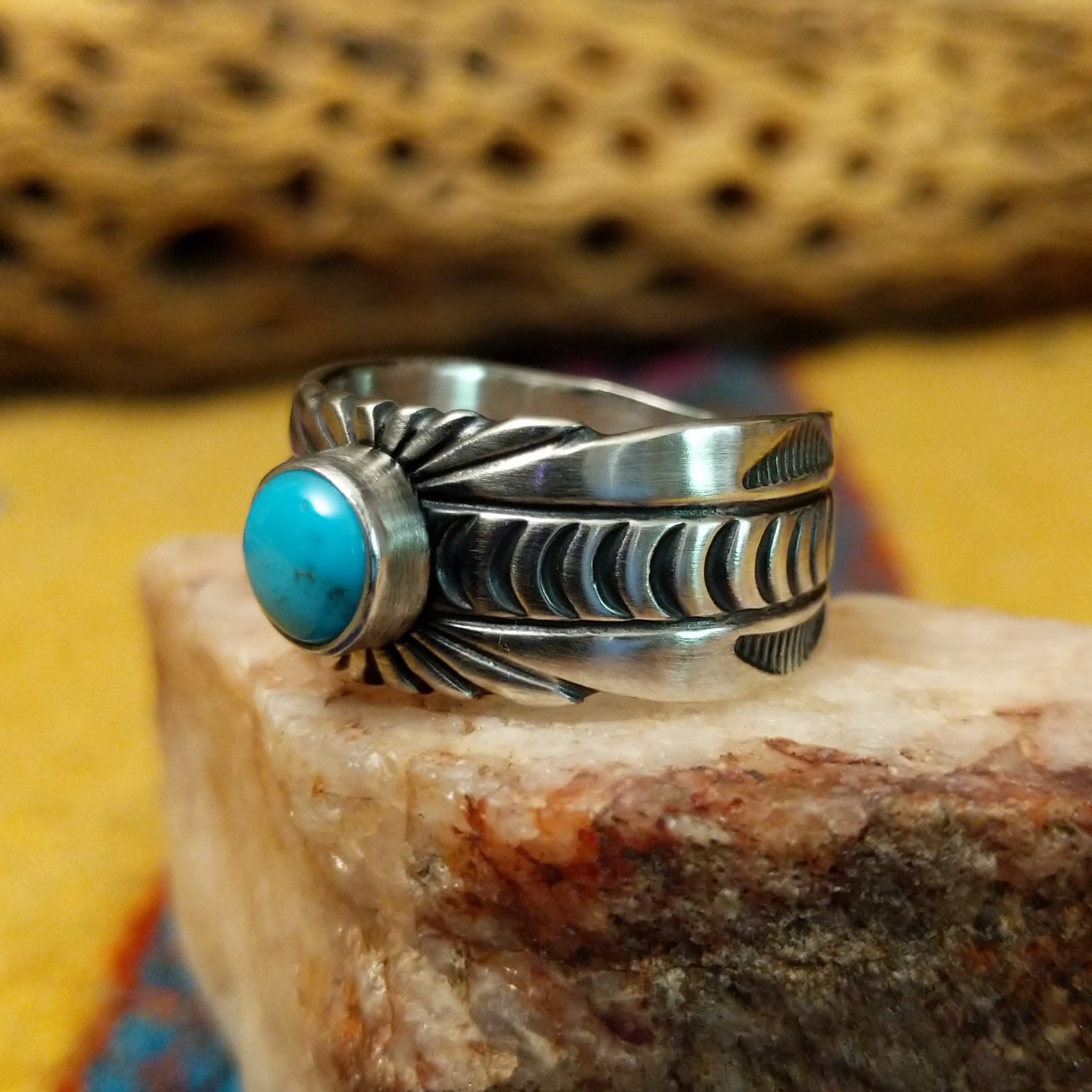 Turquoise round ring by Raymond Coriz, featuring a round turquoise stone set in a handcrafted sterling silver ring with an intricately detailed hand-stamped band. Side view.