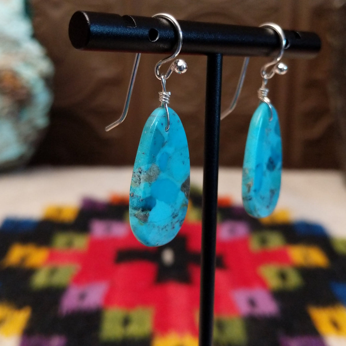 Turquoise Slab Earrings by Ronald Chavez featuring elongated freeform blue turquoise stones with natural tan, brown, and dark matrix, suspended from silver-tone hooks; side view.