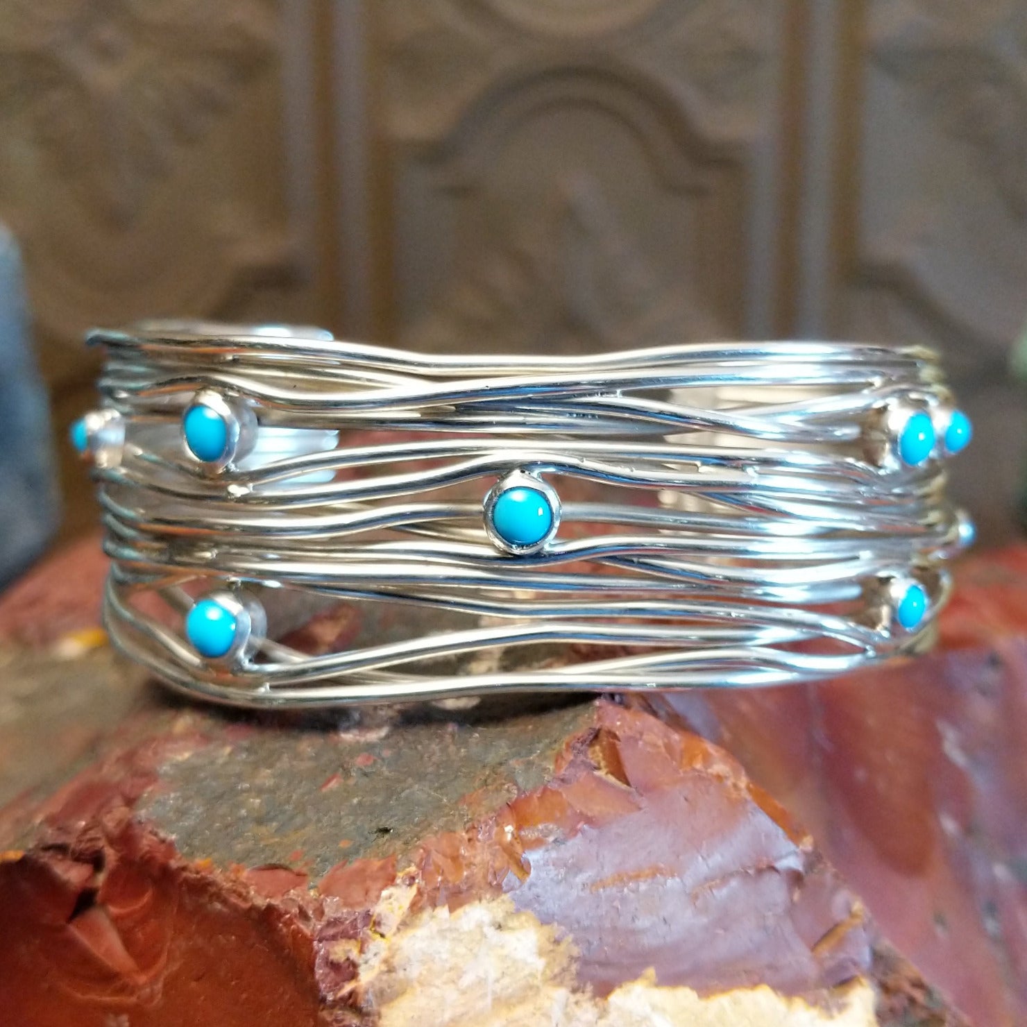 Sterling silver cuff bracelet with strands of silver intertwined and sporadic turquoise accents set in bezels.