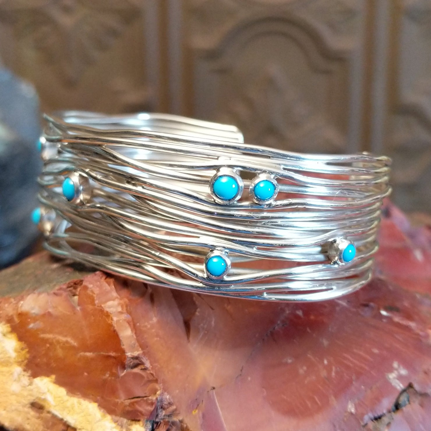 Sterling silver cuff bracelet with strands of silver intertwined and sporadic turquoise accents set in bezels.