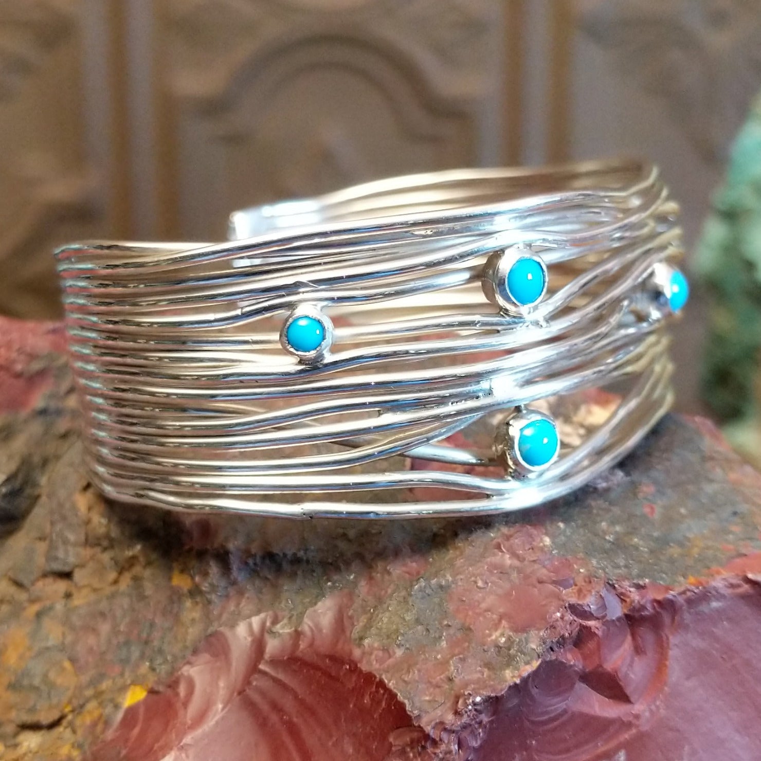 Sterling silver cuff bracelet with strands of silver intertwined and sporadic turquoise accents set in bezels.