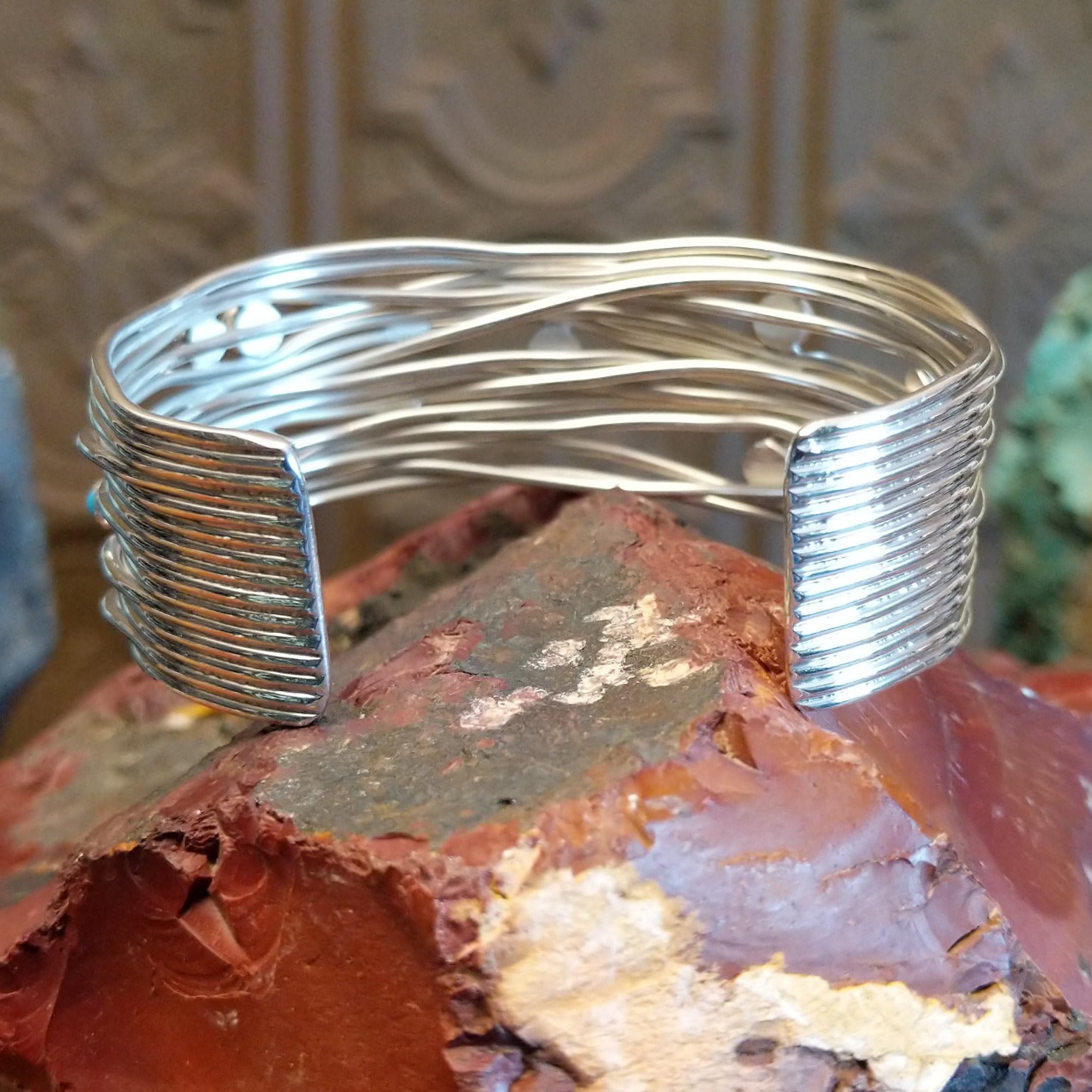 Sterling silver cuff bracelet with strands of silver intertwined and sporadic turquoise accents set in bezels.