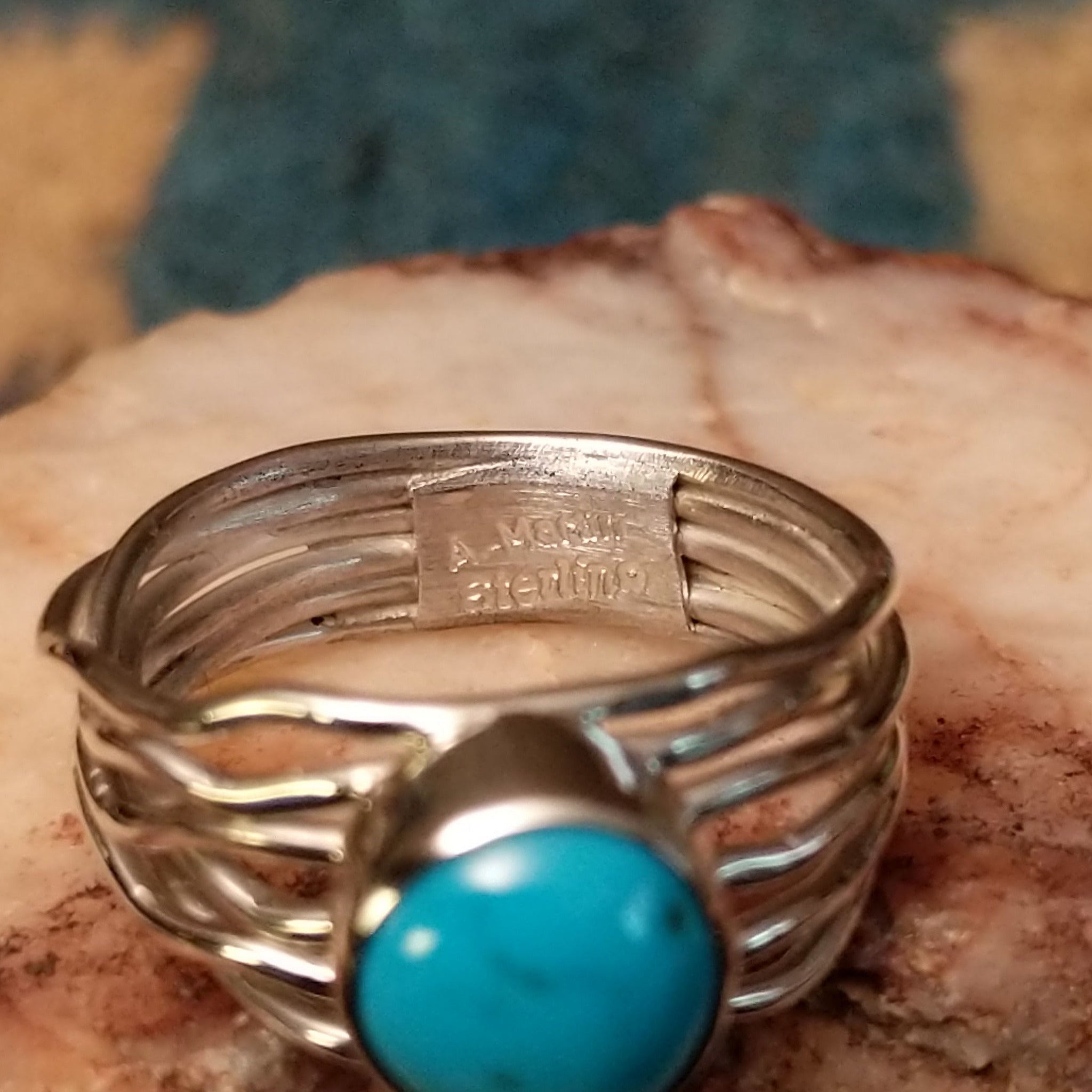 Turquoise strand ring by Angela Martin, featuring a round blue turquoise stone set in a handcrafted sterling silver multi-strand band with a polished finish. Artisan and Sterling Silver stamp.
