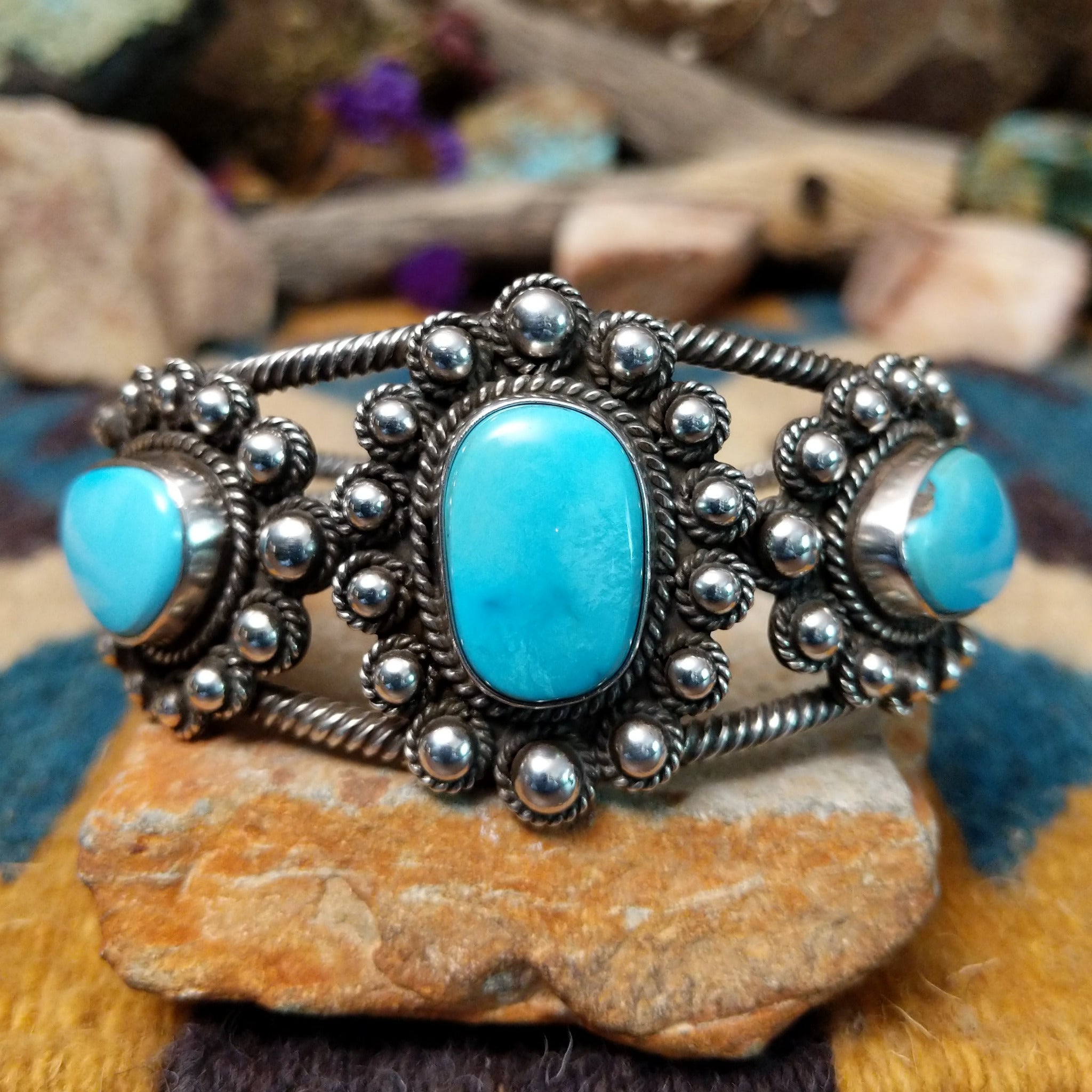 Handcrafted sterling silver cuff by Linda Johnson featuring three vibrant turquoise cabochons with twisted rope bezels, ornate silver beadwork, and a classic double-wire cuff design.