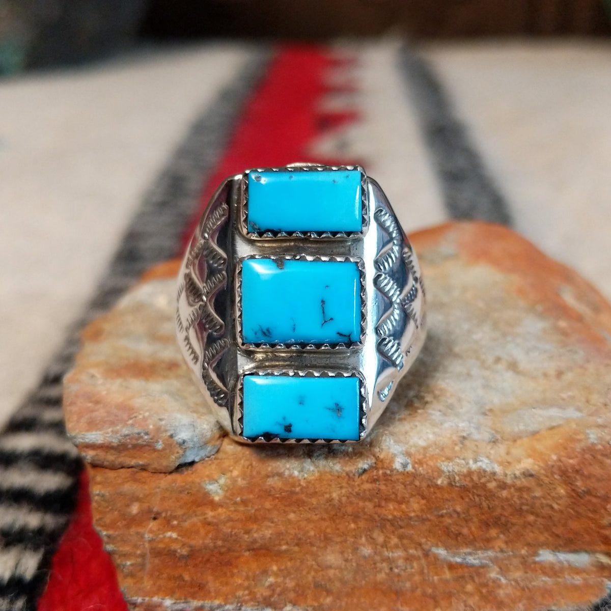 Turquoise Trio Ring by Pauline Nelson featuring three rectangular blue turquoise stones arranged vertically in serrated silver bezels, with detailed hand-stamped designs along the wide silver band.