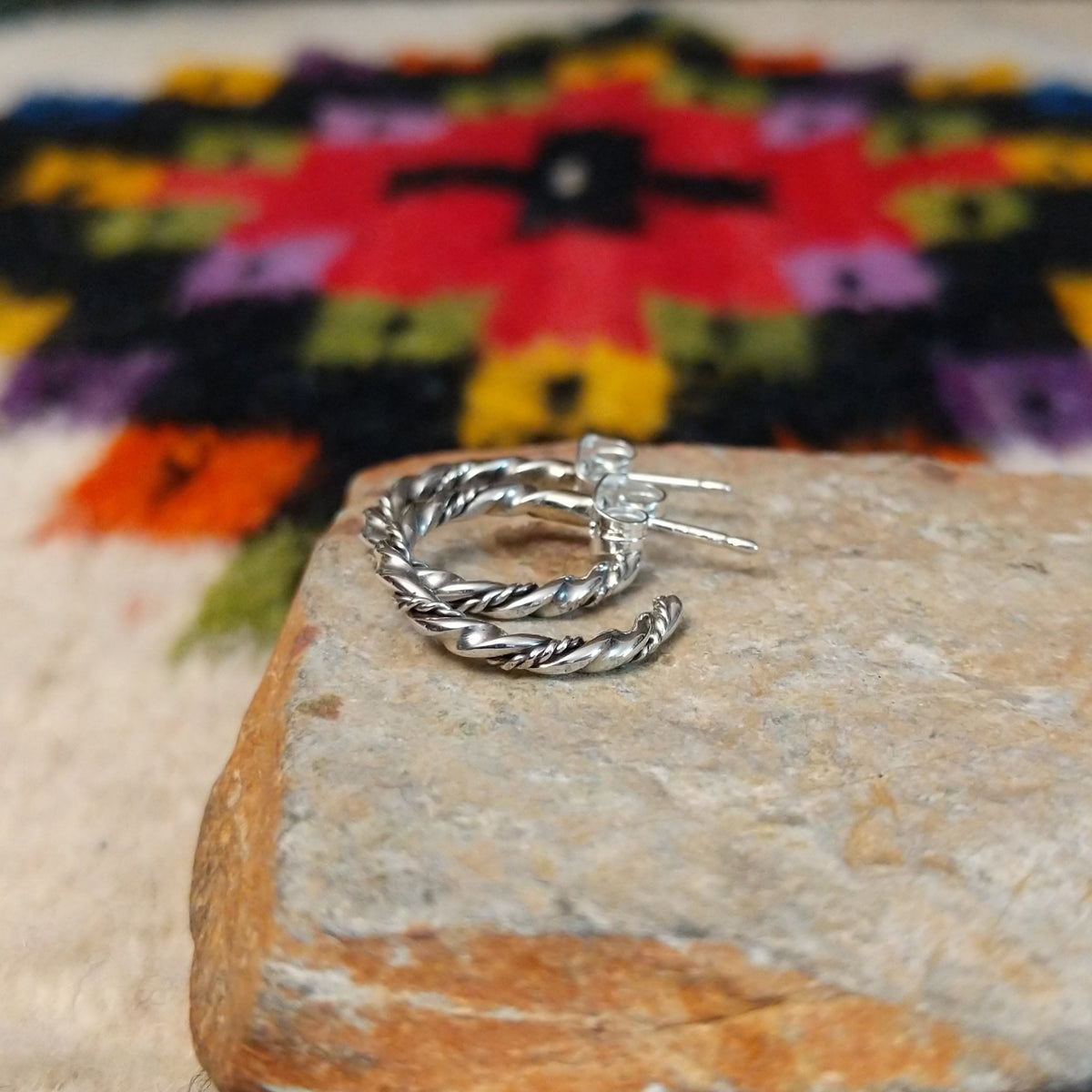 Twisting silver hoop earrings by Caroline Tsosie.