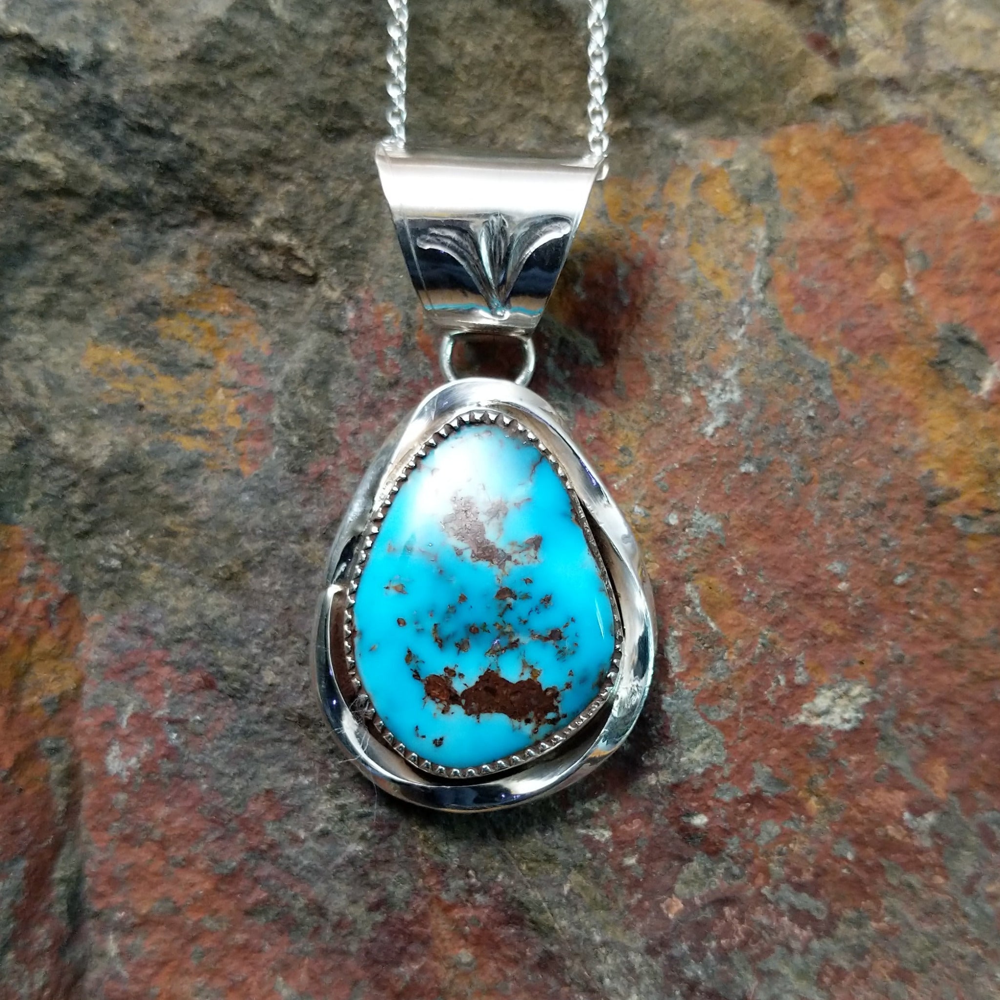 Handcrafted sterling silver turquoise pendant by Elgin Hoskey, featuring a natural blue turquoise stone with brown matrix in a smooth freeform setting.