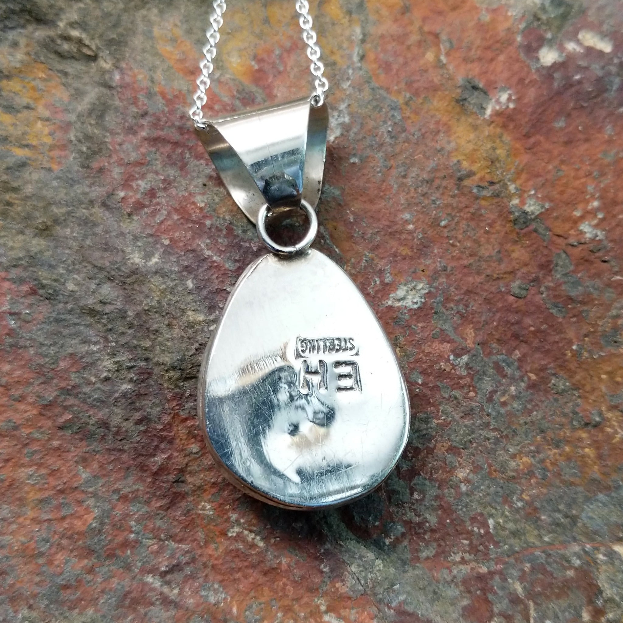 Handcrafted sterling silver turquoise pendant by Elgin Hoskey, featuring a natural blue turquoise stone with brown matrix in a smooth freeform setting; artisan and Sterling Silver stamp.