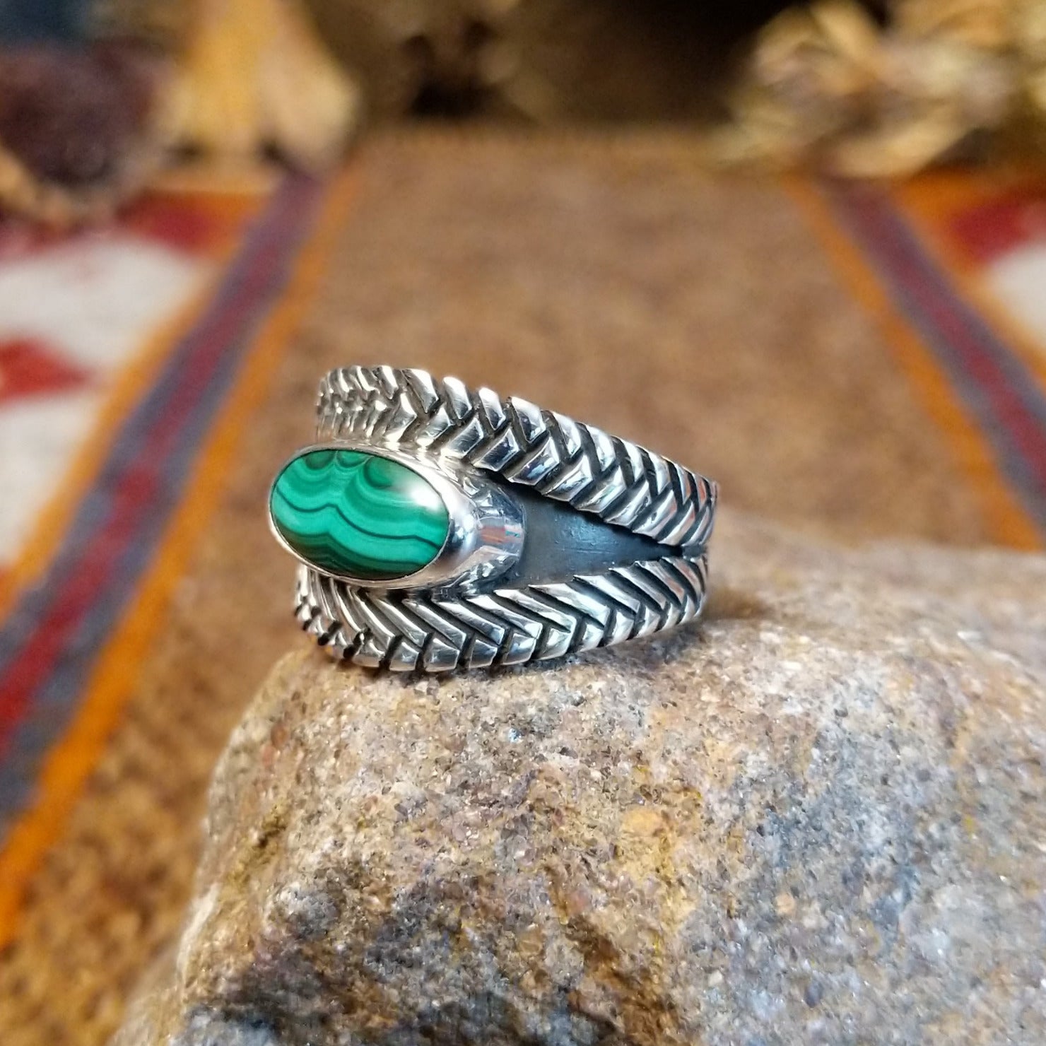 Sterling silver ring with oval malachite set in the bezel and weave patterned band.