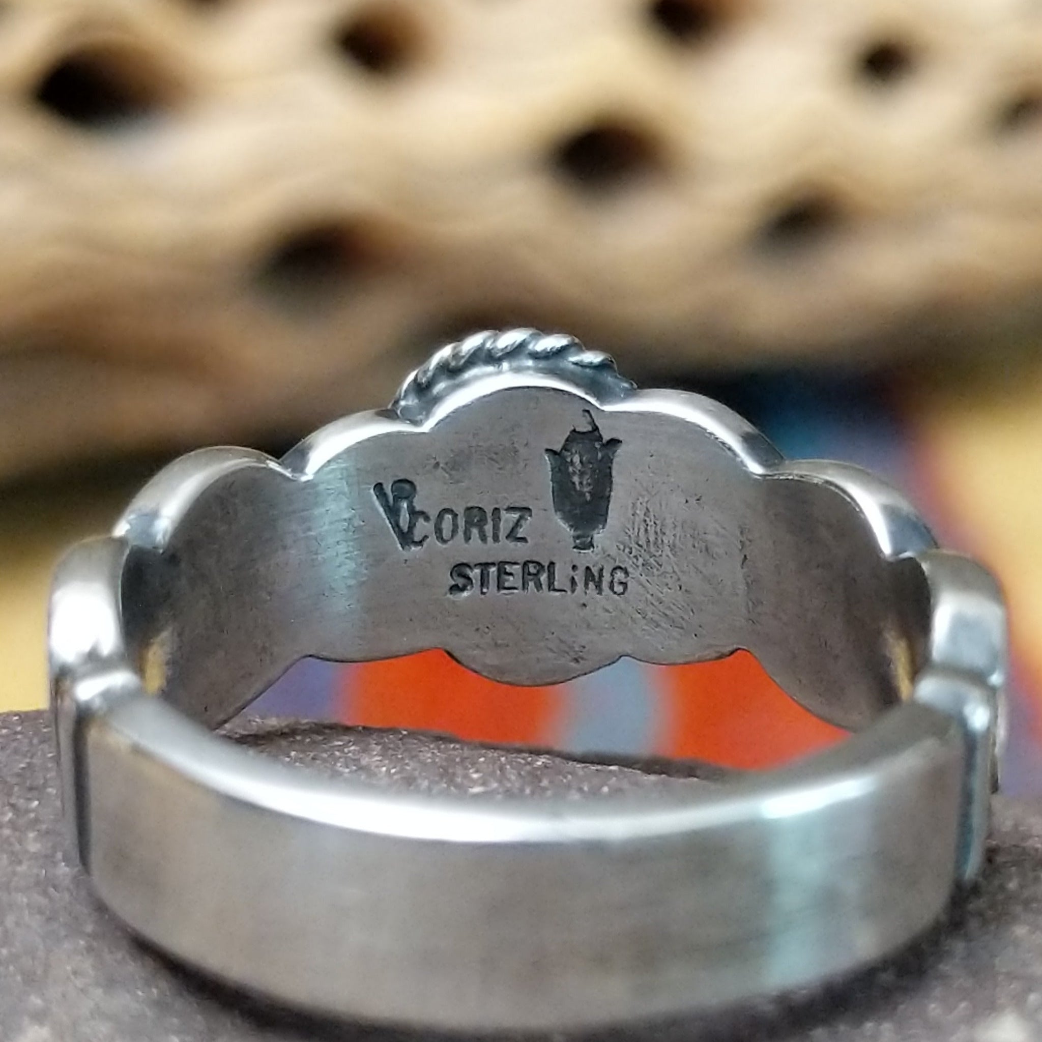 Lapis ring with weaving band by Raymond Coriz, featuring a deep blue lapis stone with natural pyrite flecks set in a handcrafted sterling silver woven band. Artisan and Sterling Silver stamp.