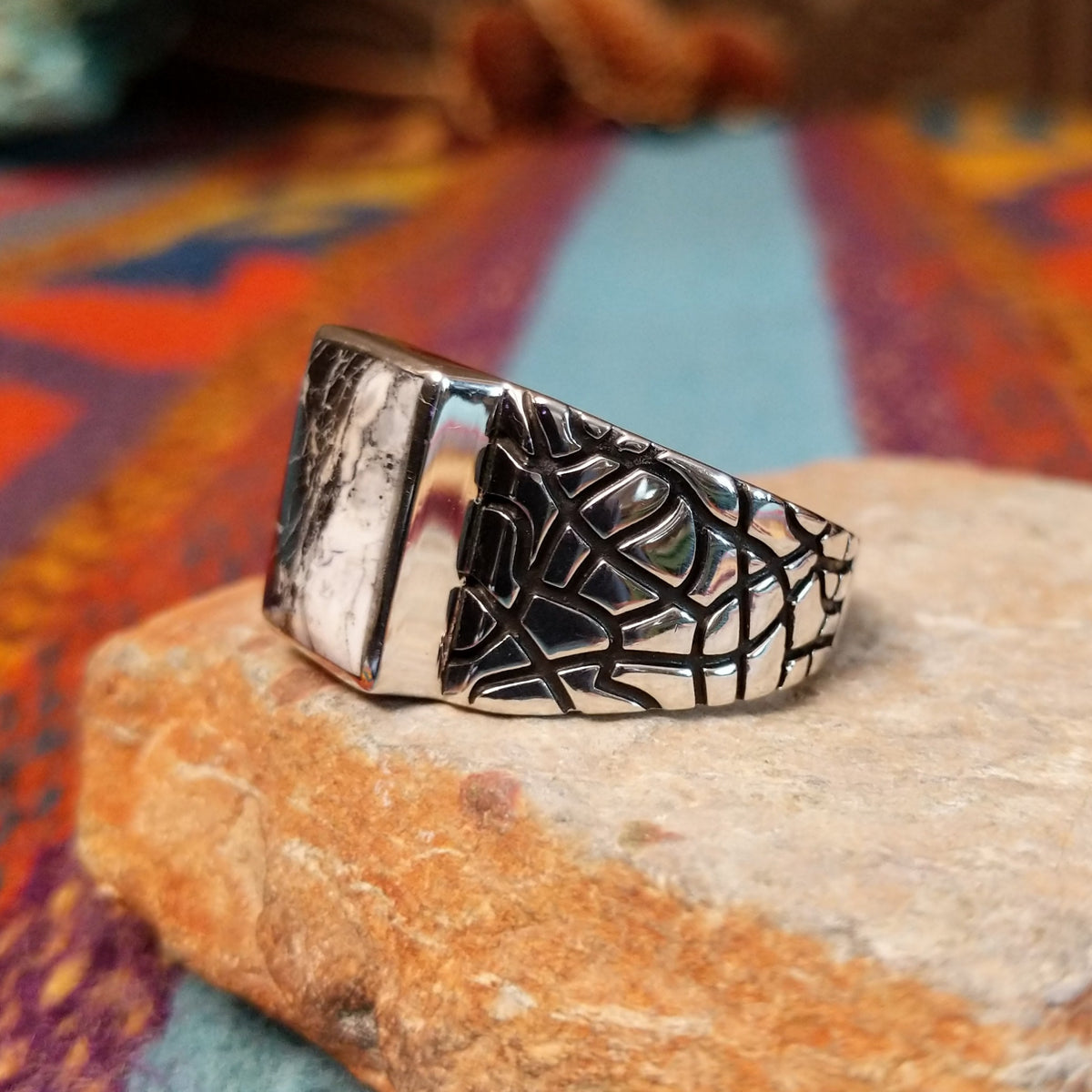 White Buffalo Ring by Terry Wood featuring a rectangular black-and-white stone with dramatic natural veining, set in polished silver with an intricate geometric openwork band; side view.