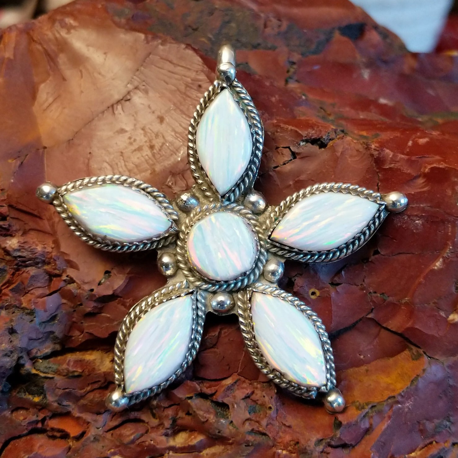 Sterling silver star pendant with manmade opal set in the bezels that are framed by twisted rope accents.
