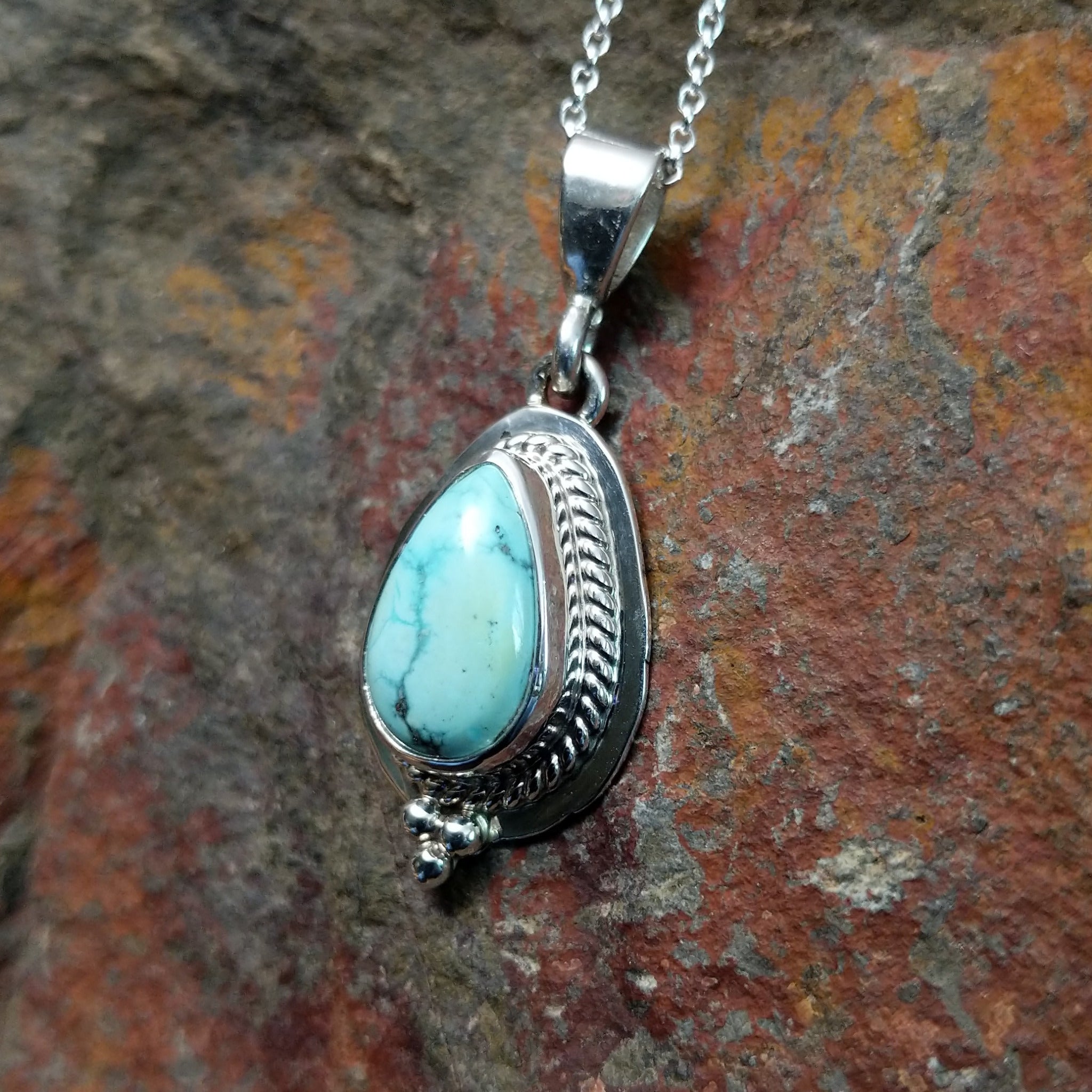 Handcrafted sterling silver White Water turquoise pendant by Lucy Jake, featuring a natural blue-green stone in a traditional Navajo setting; side view.
