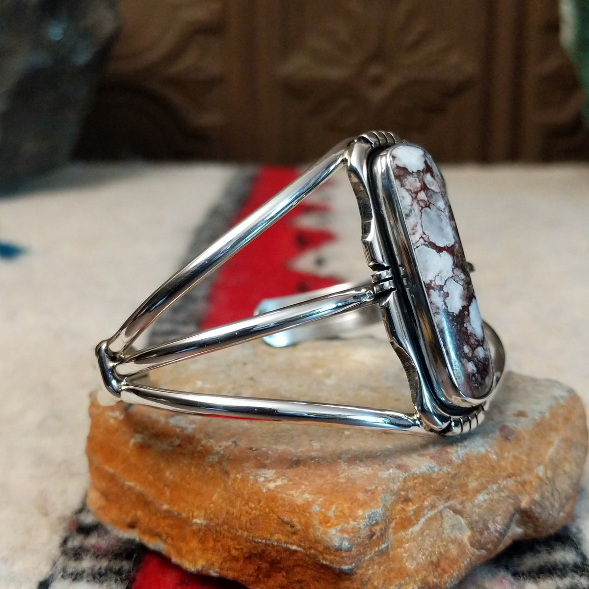 Silver cuff by Amory Begay featuring a long rectangular Wild Horse stone with creamy white and brown matrix, framed by polished silver and curved split bands; side view.