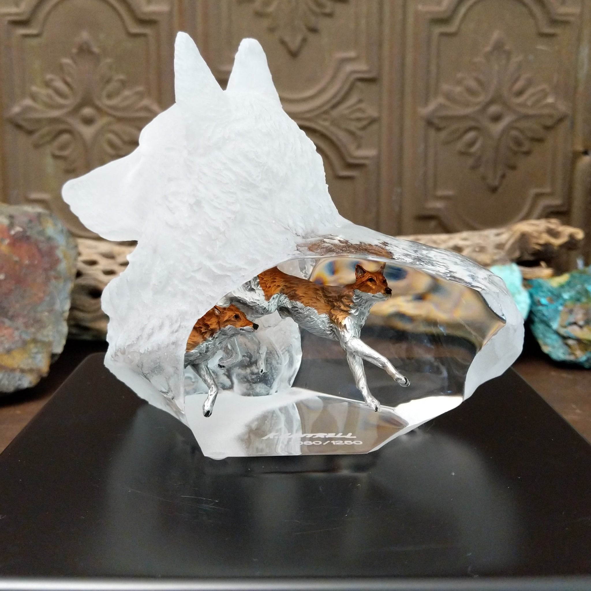 A frosted Lucite sculpture shaped like a wolf's head with a hand-painted wolf running inside the clear crystal interior, creating the illusion of movement.