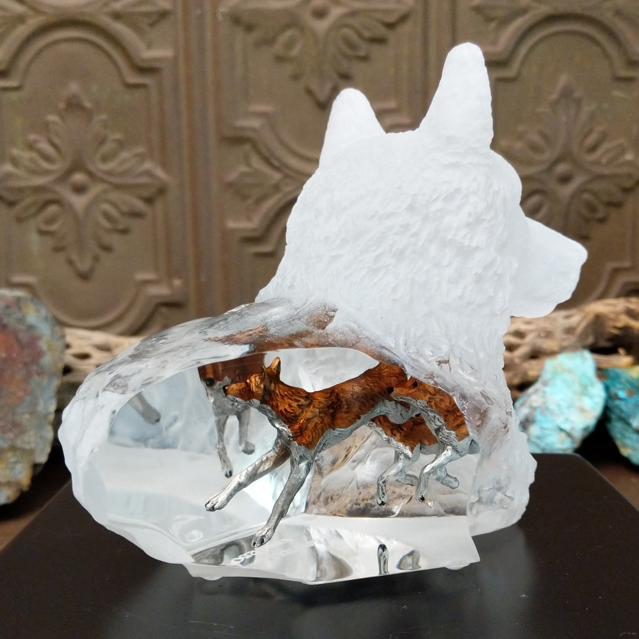 A frosted Lucite sculpture shaped like a wolf's head with a hand-painted wolf running inside the clear crystal interior, creating the illusion of movement.