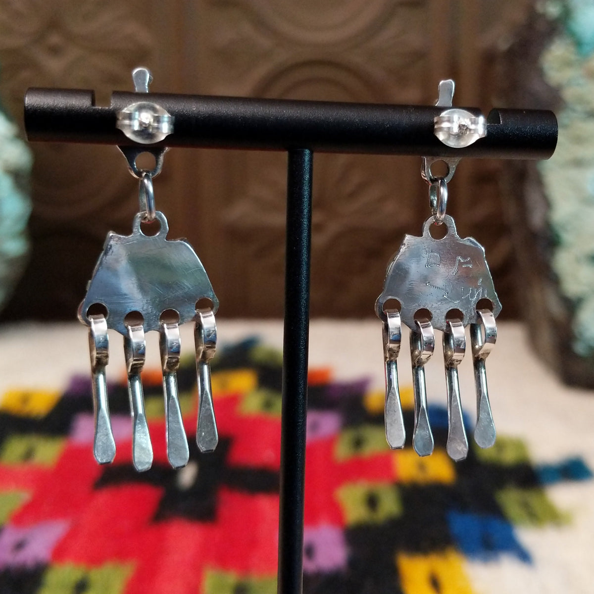 Zuni Coral Earrings featuring red-orange coral stones in detailed silver settings with clustered accents and multiple long dangling silver elements; artisan signature.