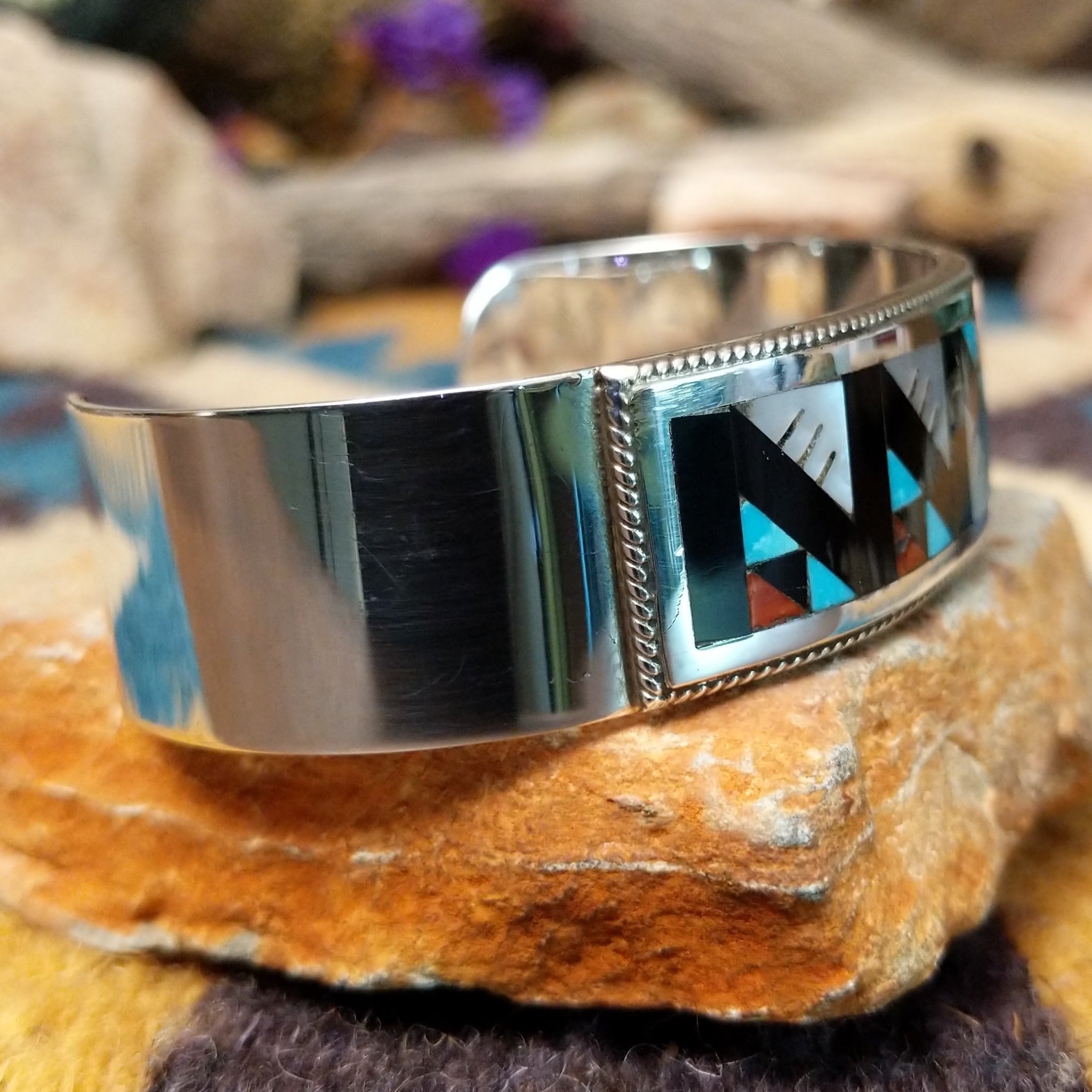 Handcrafted sterling silver Zuni cuff by Leander & Lisa Othole featuring a bold geometric channel inlay design with a polished sterling silver cuff and traditional Southwestern craftsmanship; side view.