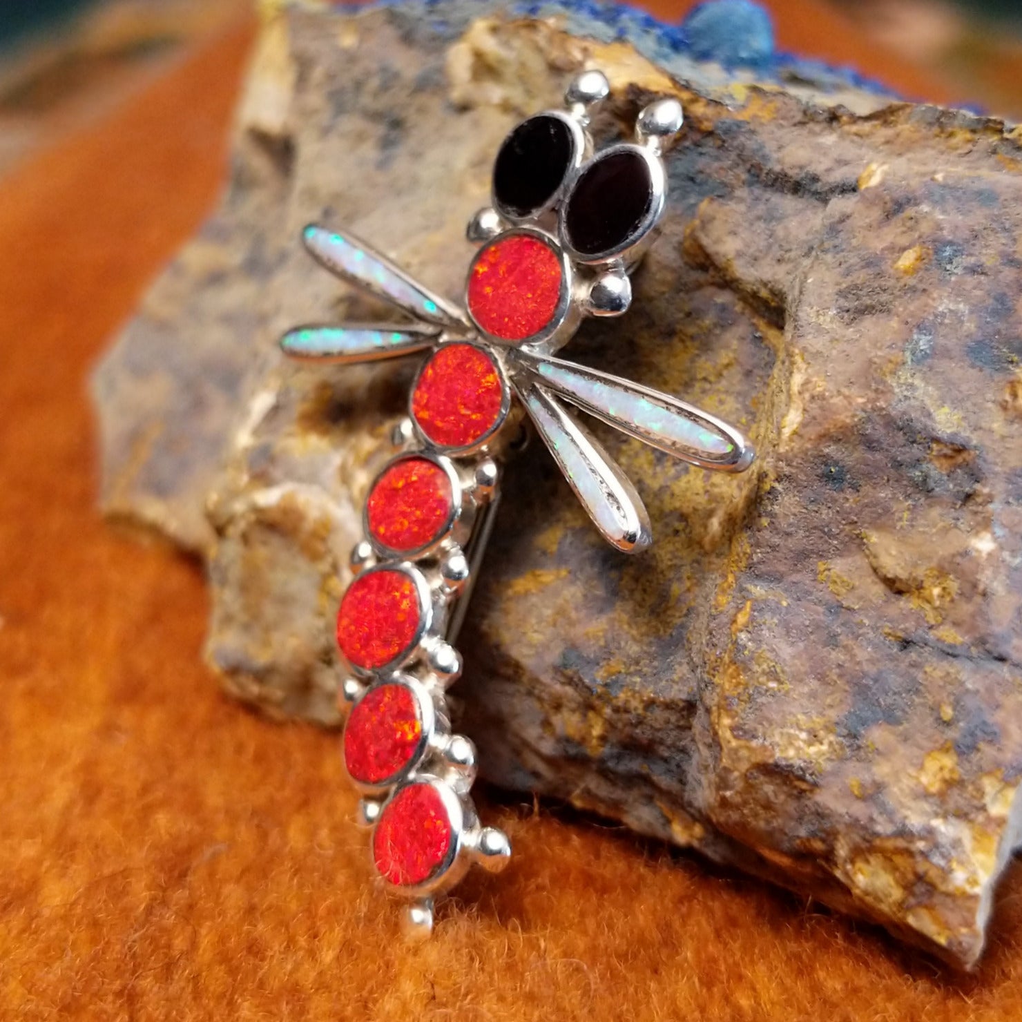Sterling silver and red manmade opal, white manmade opal, and black onyx along the body of the dragonfly pendant.