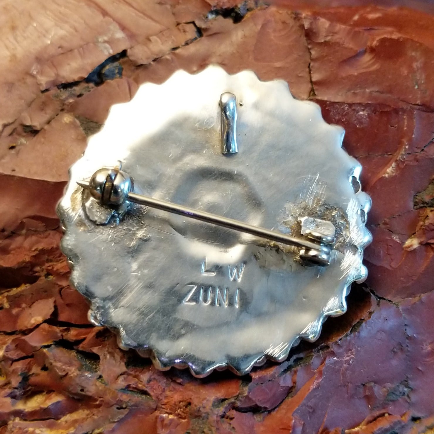 The back features the pin and the artisan's stamped initials.