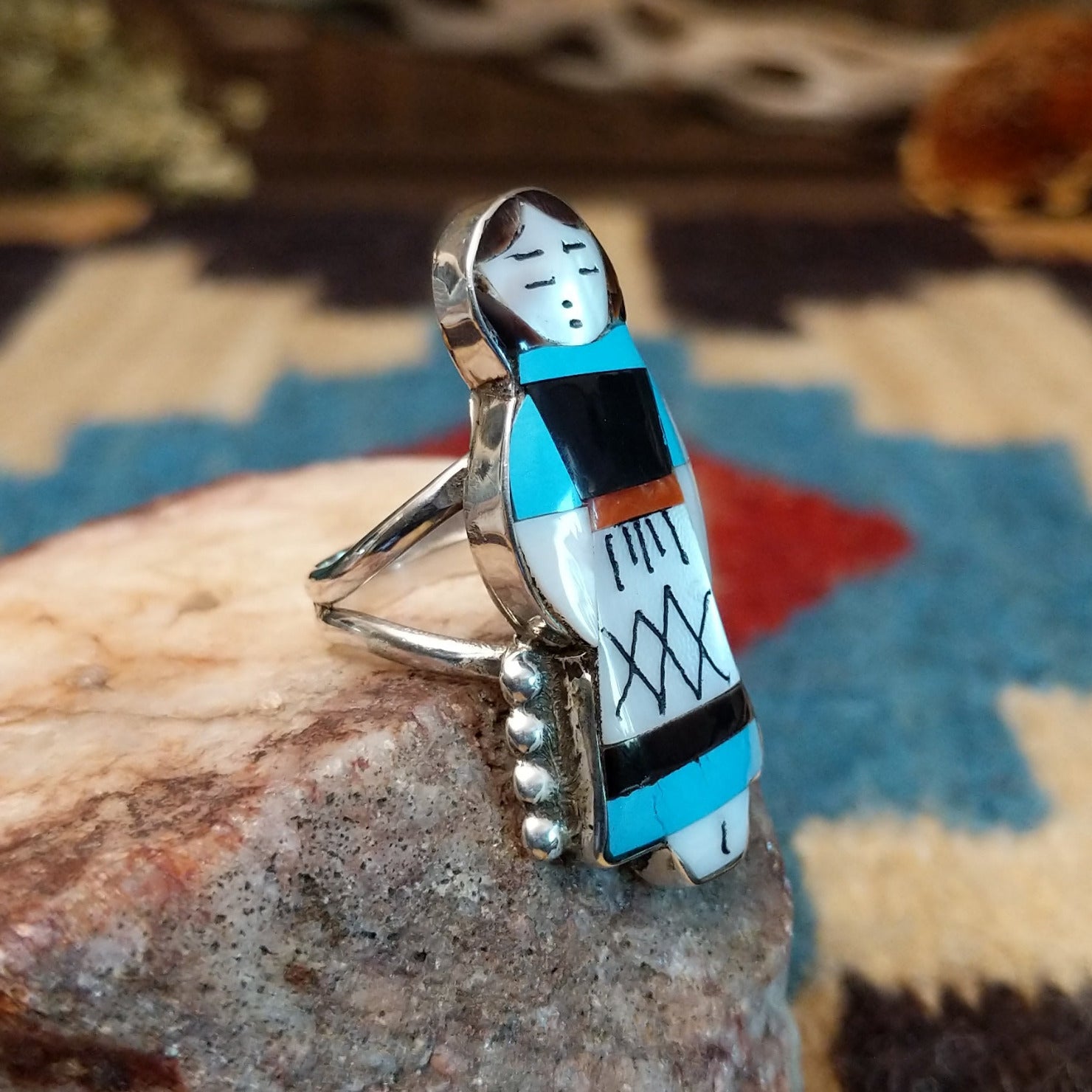 Sterling silver ring with maiden motif featuring turquoise, black onyx, coral, and mother of pearl.