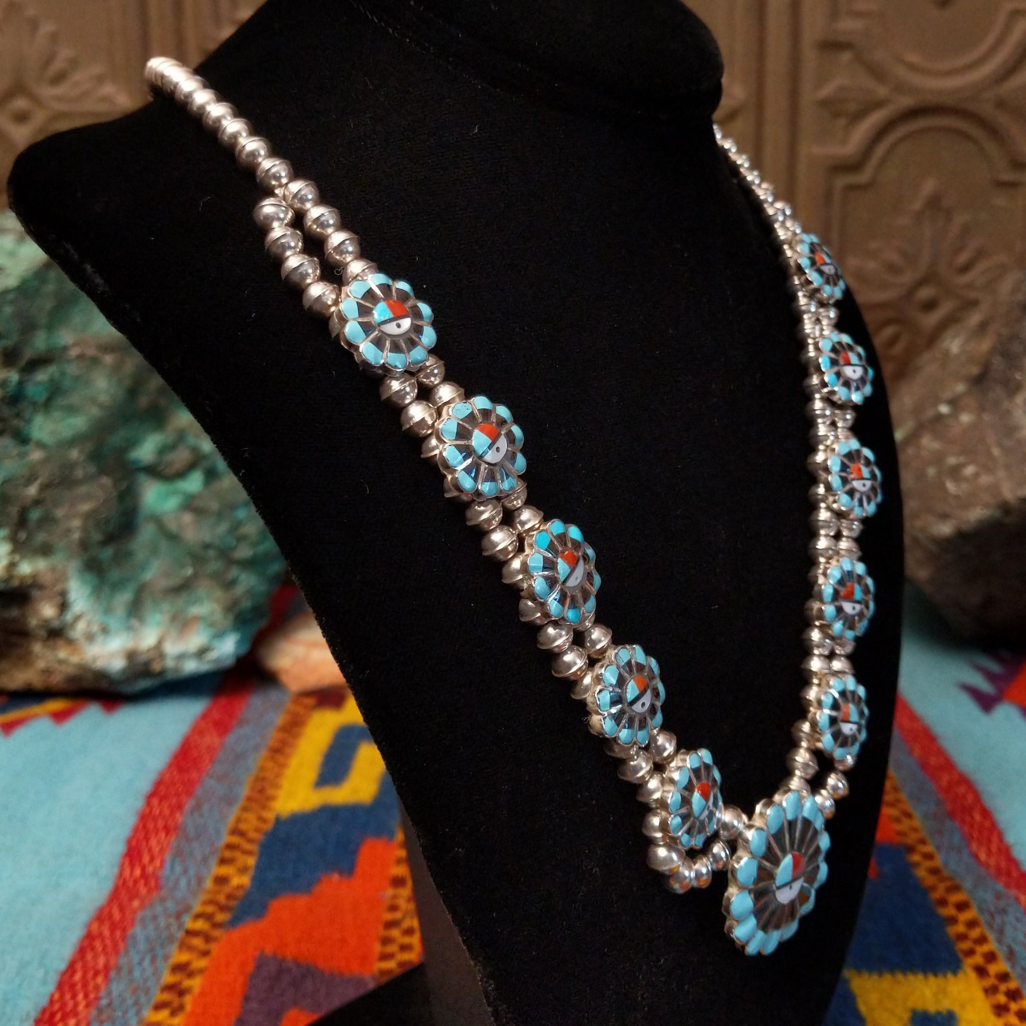 Zuni Sunface Sterling Silver necklace by Marisa Selecion, featuring turquoise, coral, black onyx, and mother of pearl, with detailed Sunface designs; side view.