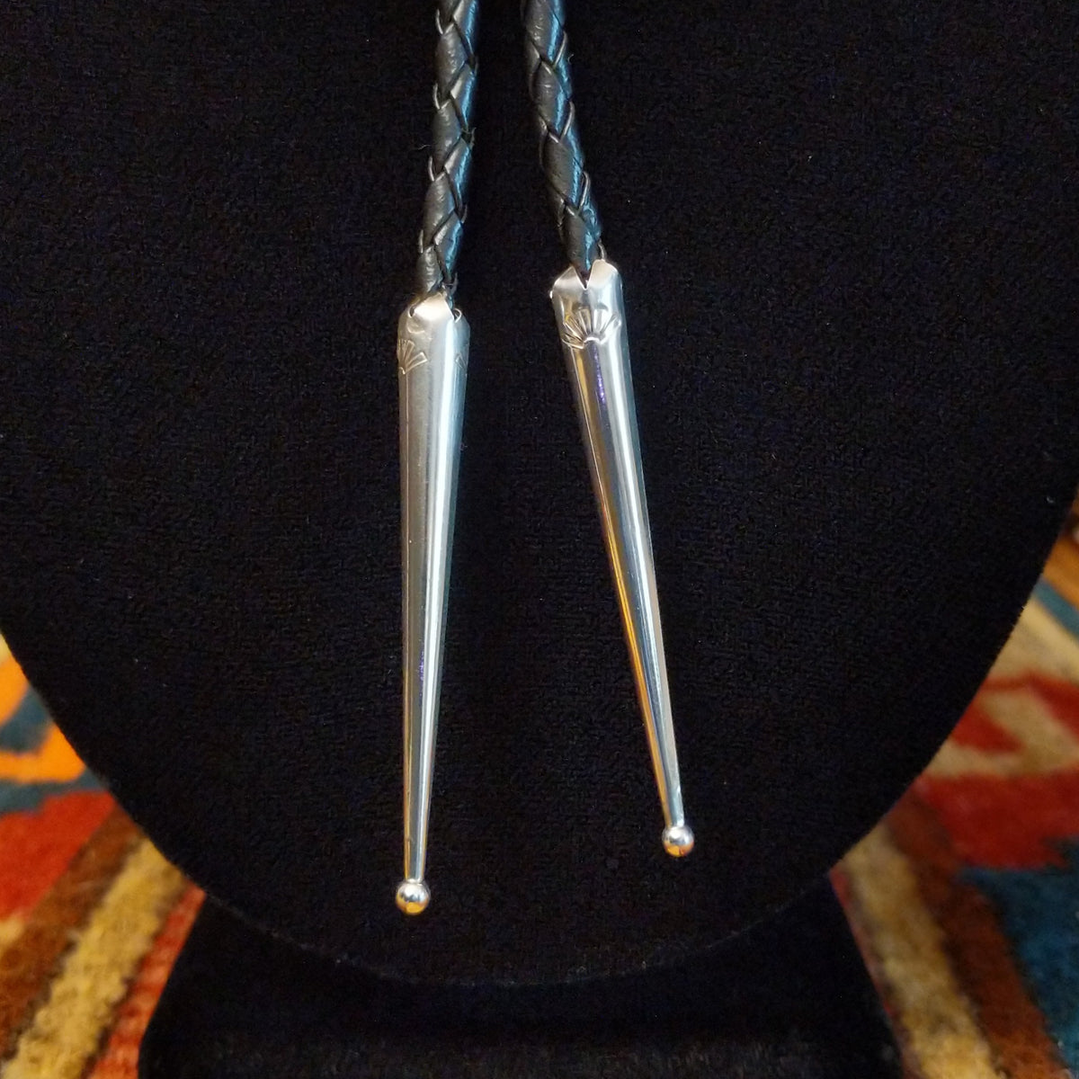 Zuni Thunderbird Bolo Tie by Bobby Shack featuring a detailed silver thunderbird with colorful turquoise, coral red, white, and black geometric inlay, outstretched wings, braided black leather cord, and polished silver tips.